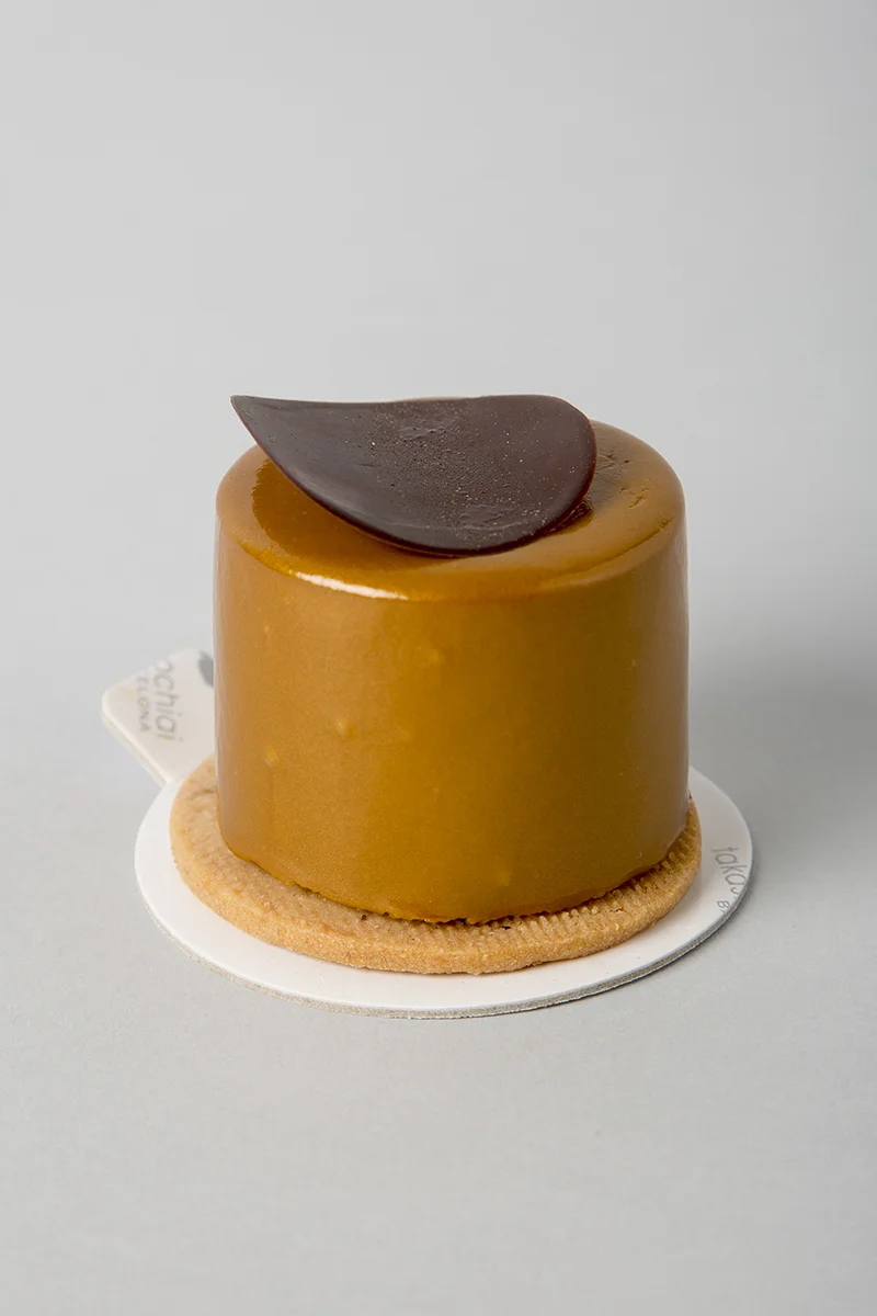 Galleta de limón, bizcocho, crema de limón, plátano caramelizado, mousse de chocolate con leche Jivara al 40% y baño de chocolate con leche.