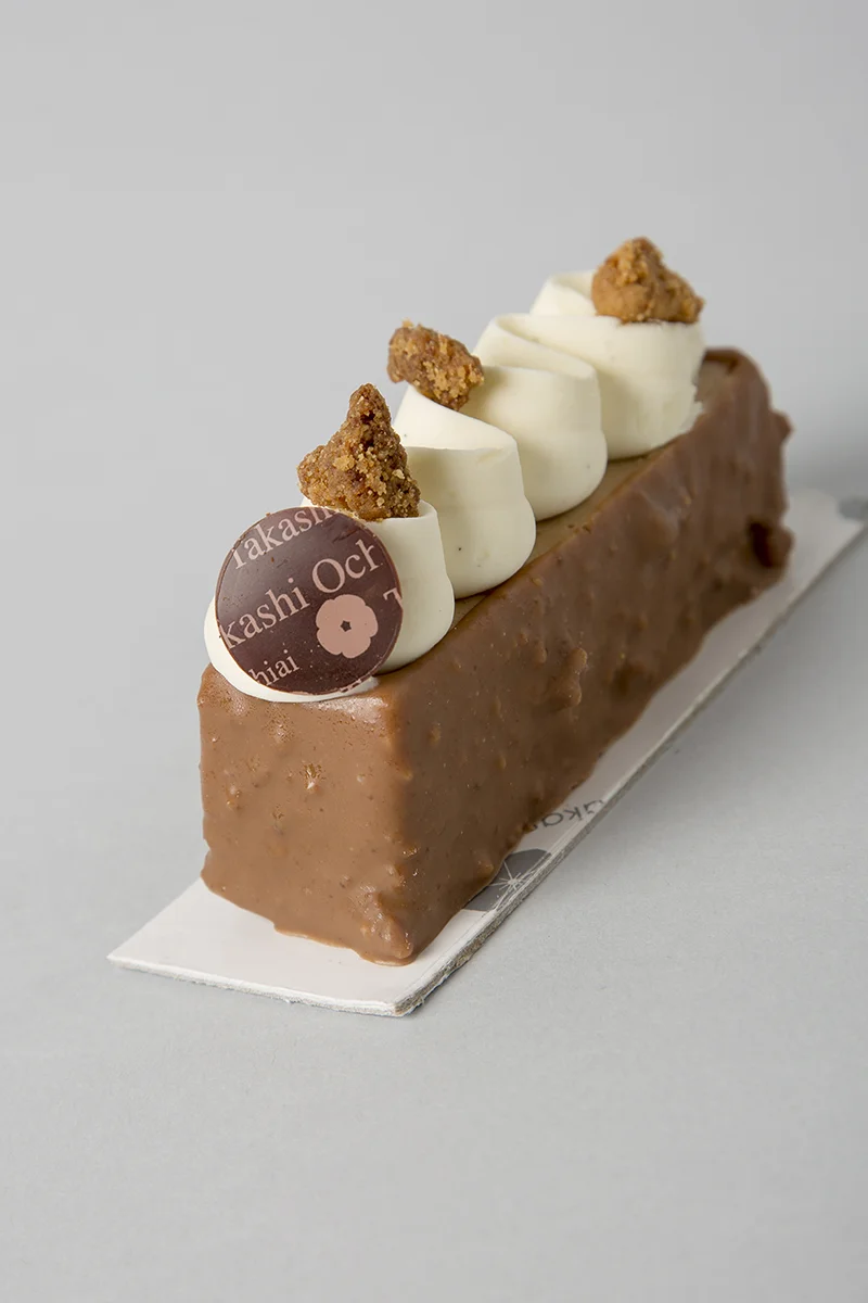 Toke. Dacquoise de avellana, crujiente de gianduja y barquillo, cremoso de chocolate y café, mousse de gianduja, baño de chocolate con leche y barquillo y ganache de vainilla con especies de haba tonka.