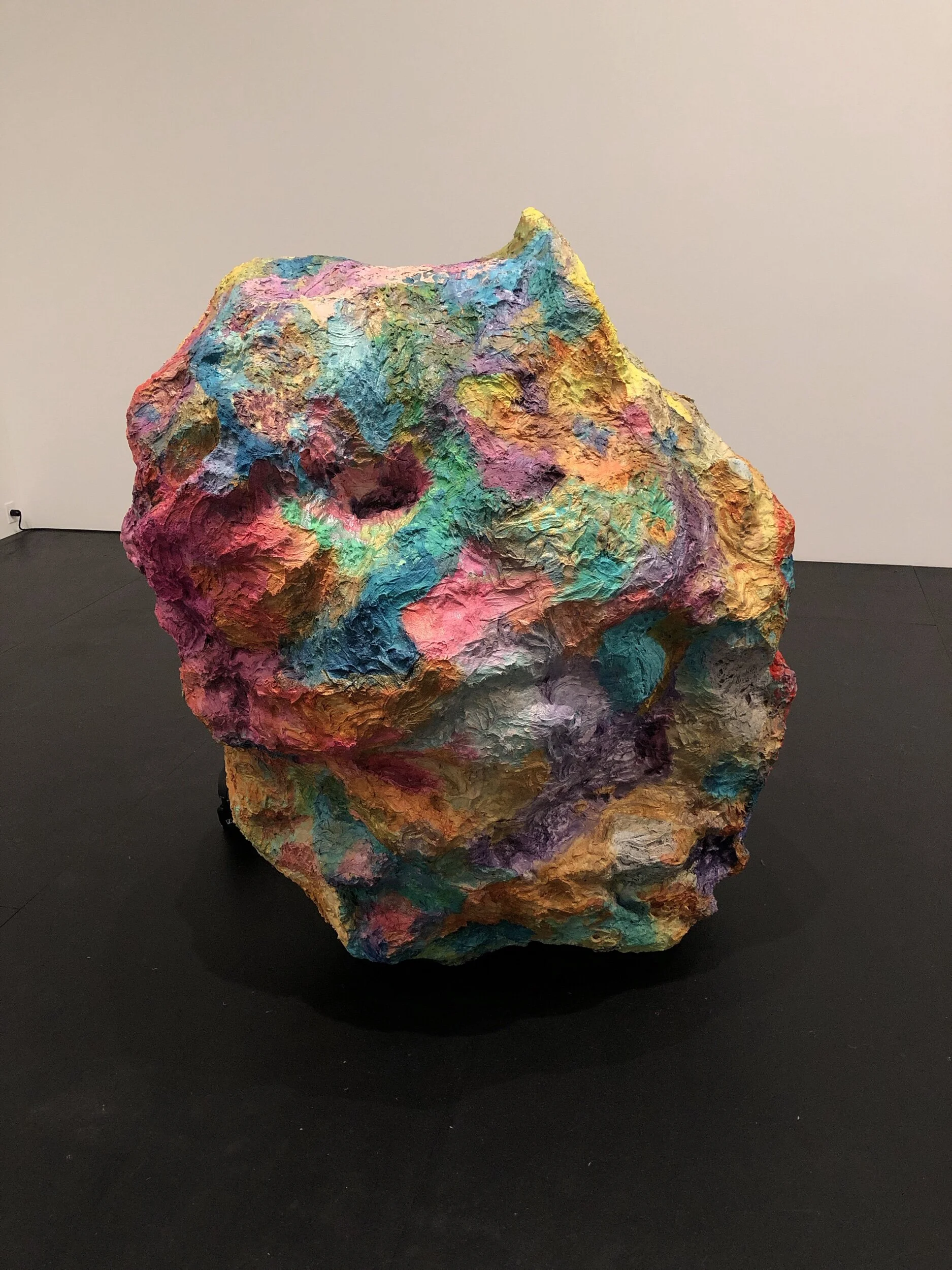 Hoarders, 2012 This piece requires you to see it in the round to appreciate it: sculpture requires movement. What looks like a boulder from one side is seen propped up by a metal bucket on the other, while a video plays on a flat screen where a taxi driver she filmed talks about the way the one percent in this country hoard their wealth. The driver mentions the A&E show “Hoarders,” and compares the hoarders on the show with the hoarding of the wealthy. This echoes the hoarding of food in Mason jars and ziplock bags in the previous gallery, the idea of accretion evident in her sculptures, the gathering of stones and bricks in handbags, etc. The piece looks heavy, but the boulder is made of wood, polystyrene, chicken wire, with cement glue and acrylic: it is hollow and actually quite light.
