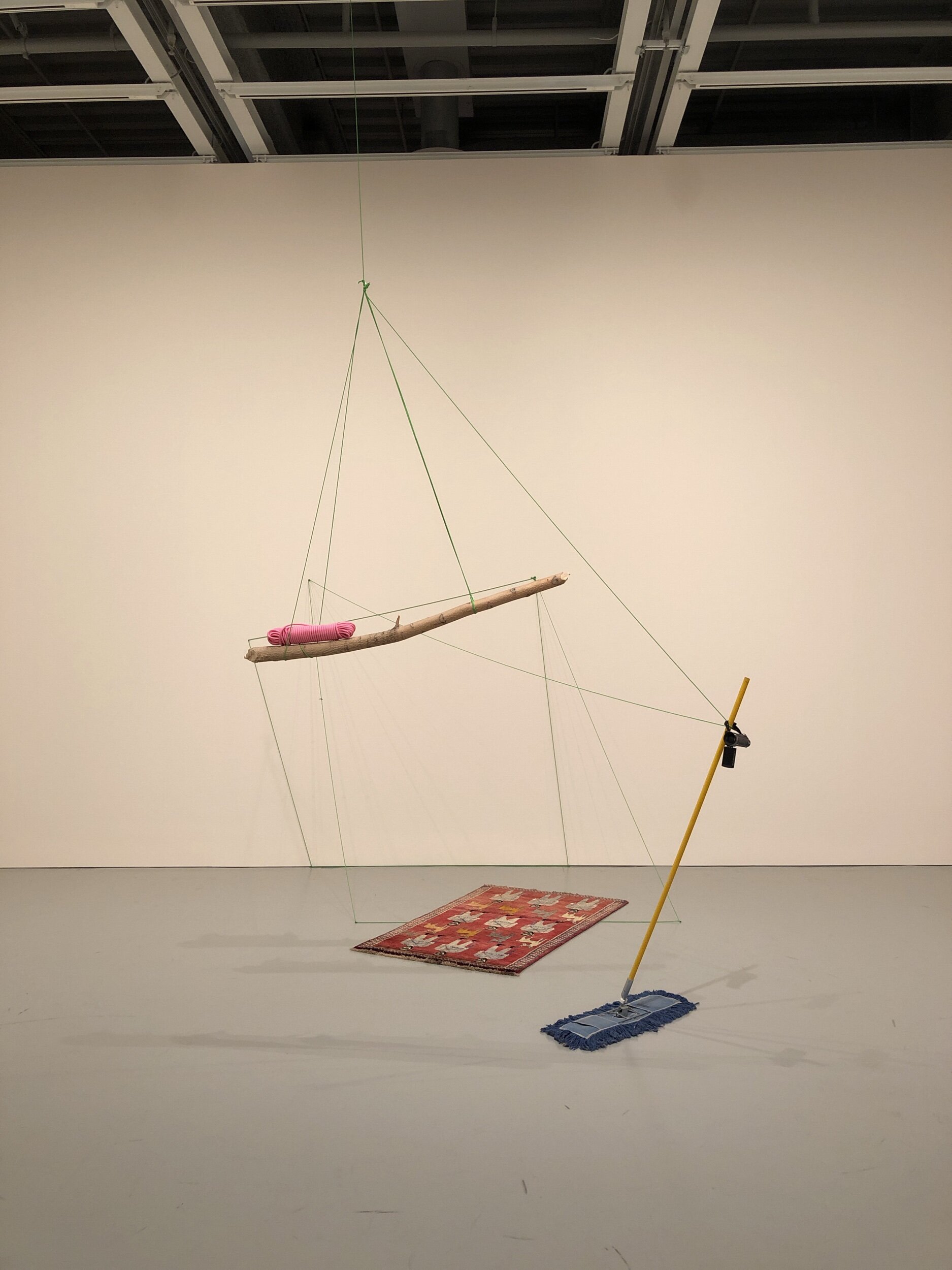 Full HD, 2019 Harrison made a sculpture entitled “Every Sculpture Needs a Trap Door” that incorporated a print out of an Andrea Fraser essay titled “Why Does Fred Sandback’s Work Make Me Cry?” Presumably Harrison included this essay as a reference to Sandback’s work, which created an illusion of demarcated space using taunt lines of yarn. Full HD seems to reference Sandback in this sense. The minimal nature of this work can be contrasted to the materiality of the works in the previous gallery: it is a stark transition. If you think of the previous gallery as being full of bombast, this is a quiet rejoinder, a self-deprecatingly spare way to close the exhibition. Perhaps the title is an ironic commentary on the low tech nature of the sculpture, including the old video camera that is presumably not filming in HD. In any event, the camera is pointed at the wall of the gallery so any HD filming will be of a blank wall. The title might also be a reference to the fact that what we see with our own eyes, like this sculpture, is full HD without the use of technology. The phrase “Full HD” suggests that we are about to see something amazing that is worthy of the technology, like a school of fish on a coral reef or a drone flyover of the Grand Canyon or Manhattan. Instead, we get a full HD view of a broom, a rug, a branch, and some cords.The broom echoes the mop at the start of the exhibition: these two mundane cleaning objects bring us full circle. Like other sculptures, there are no caution strips, there is no barrier to getting too close to the work. Given how fragile the work is, leaving it exposed in this way is especially risky.