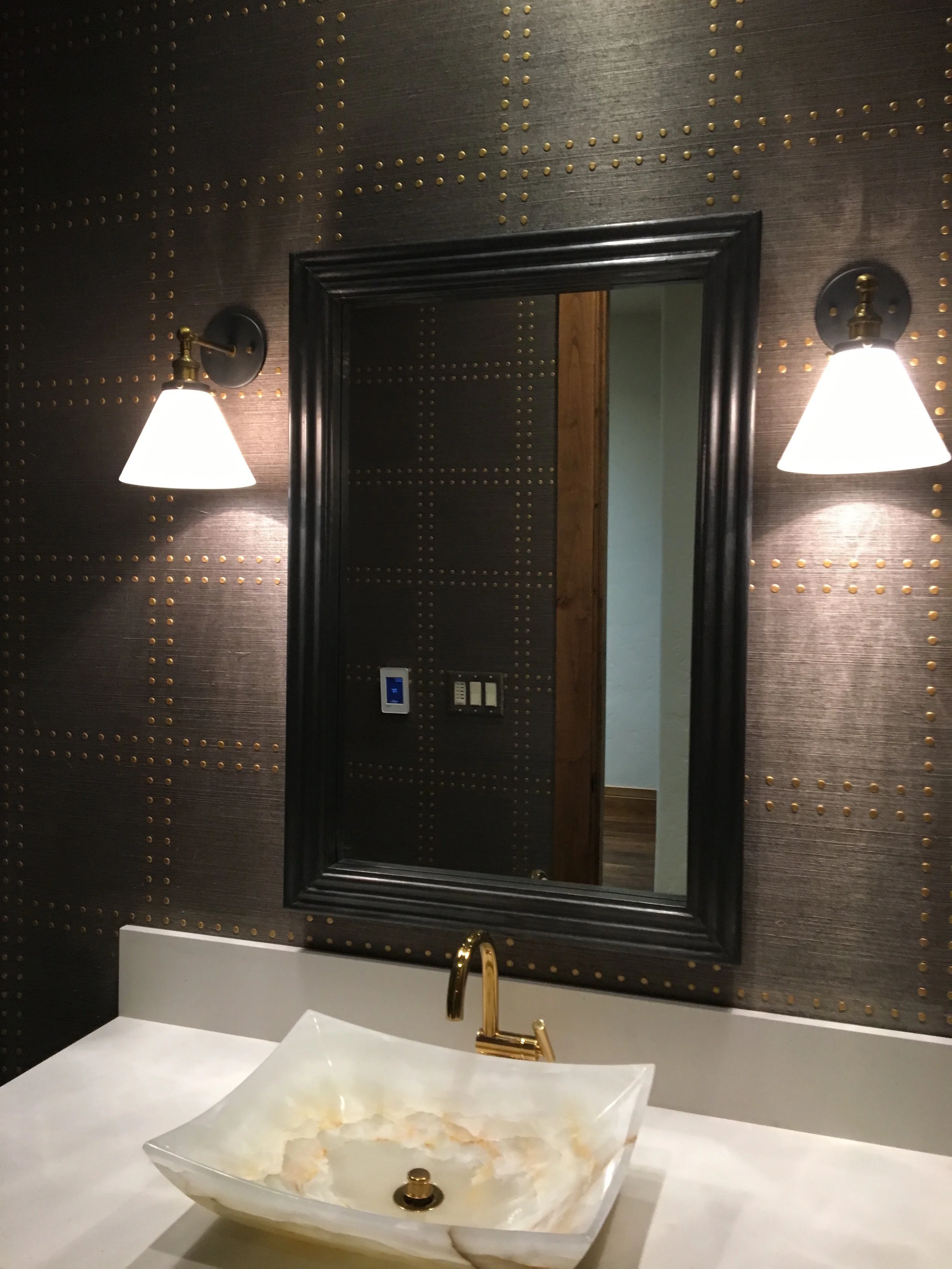 This textured wallpaper embellished by gold rivets adds interest in a powder bath. The hemp material can be wiped gently to clean and is a great option in a minimal use area.