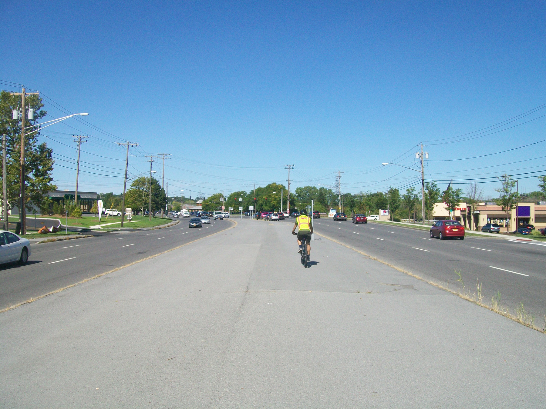 A cyclist rides down the middle of the asphalt median on Erie Boulevard East in DeWitt