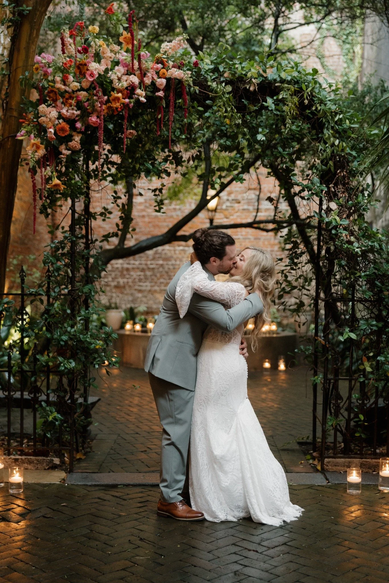 Newlyweds kissing beneath the Pharmacy Museum floral arch
