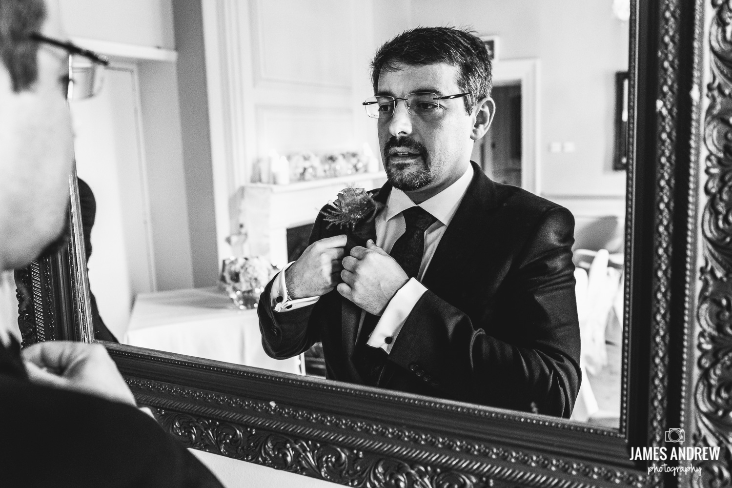 Groom looking in mirror before getting married