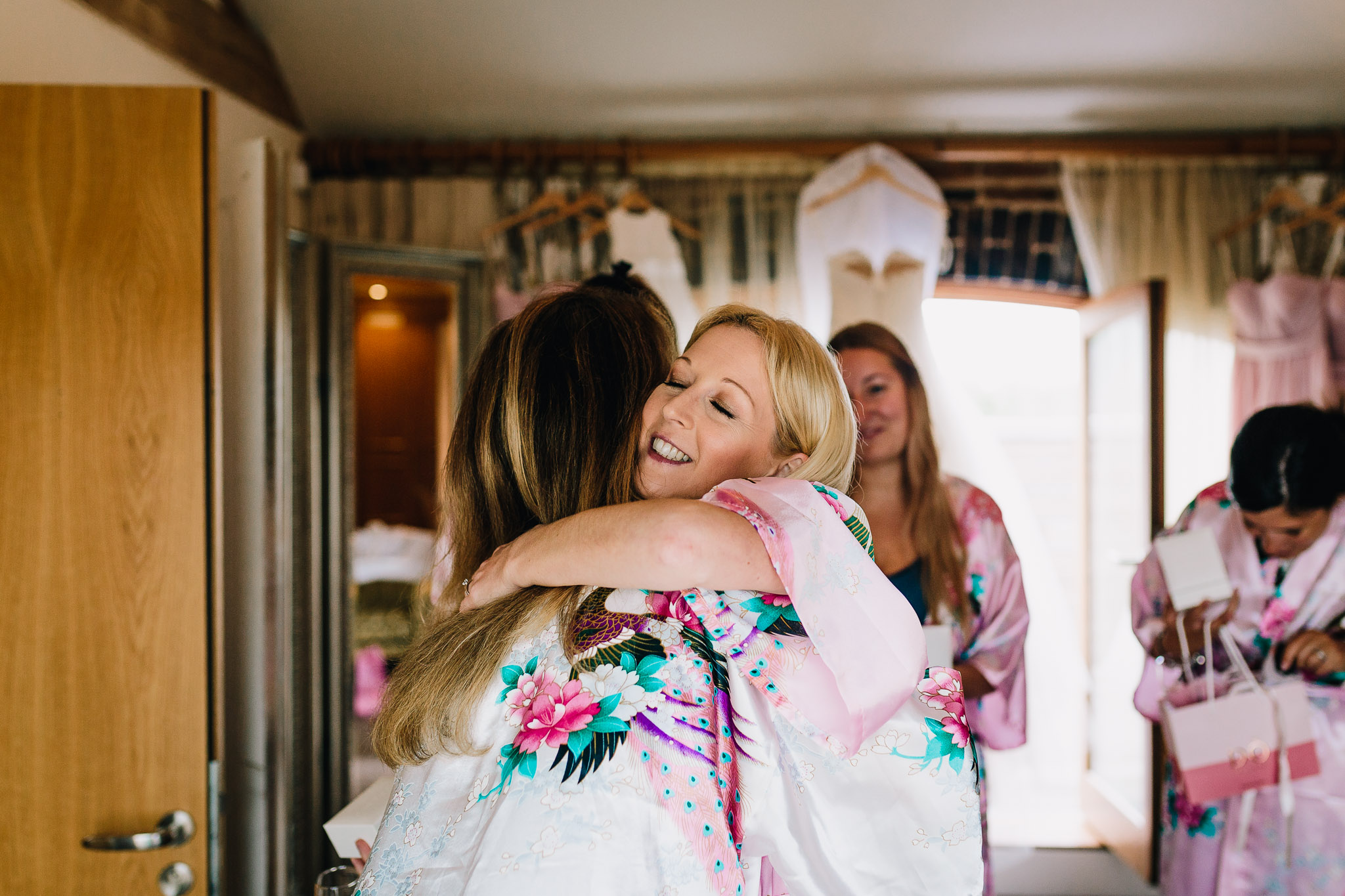BRIDESMAIDS HUGGING BRIDE ON WEDDING DAY