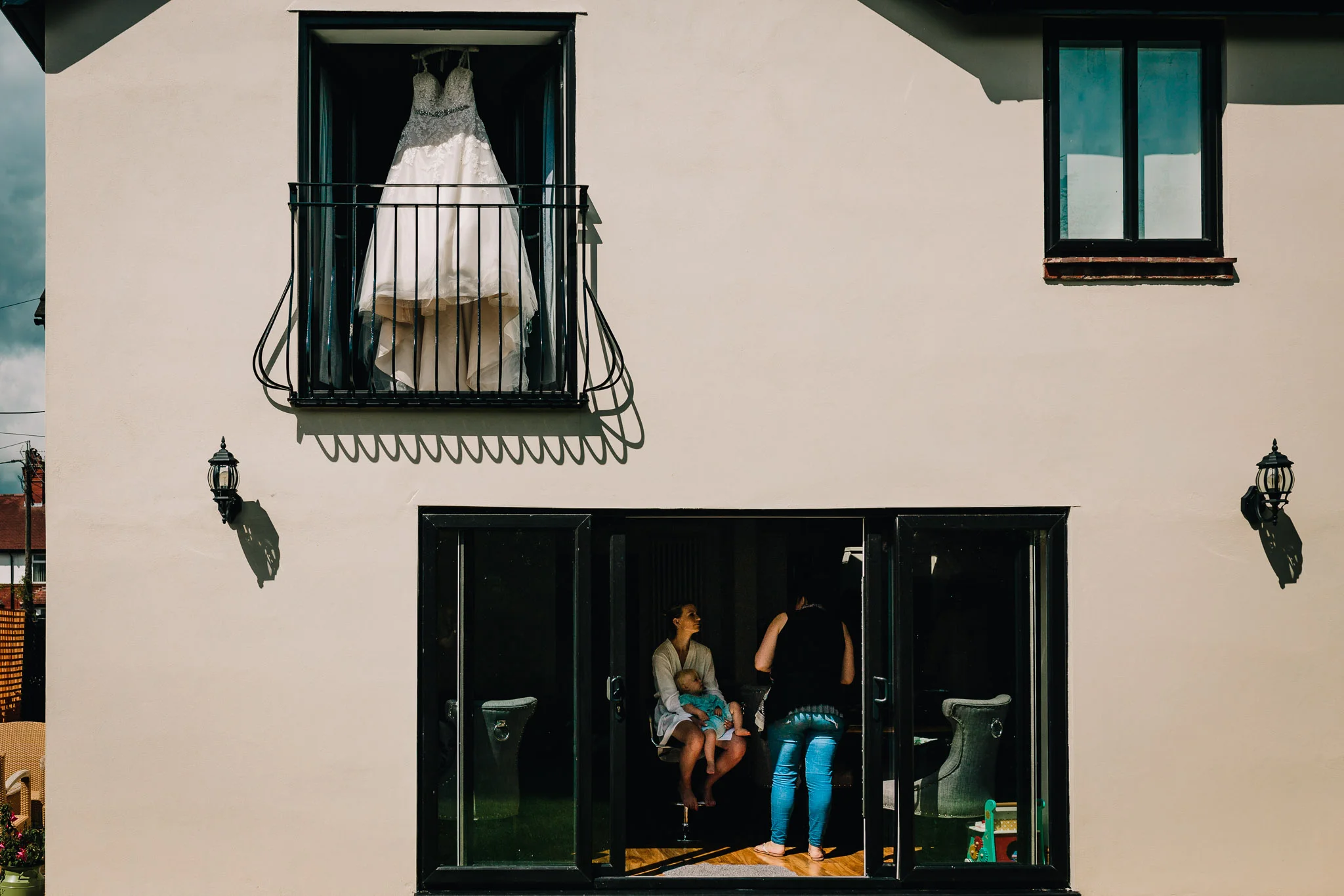 BRIDE GETTING READY AT HOME DRESS HANGING IN UPSTAIRS WINDOW
