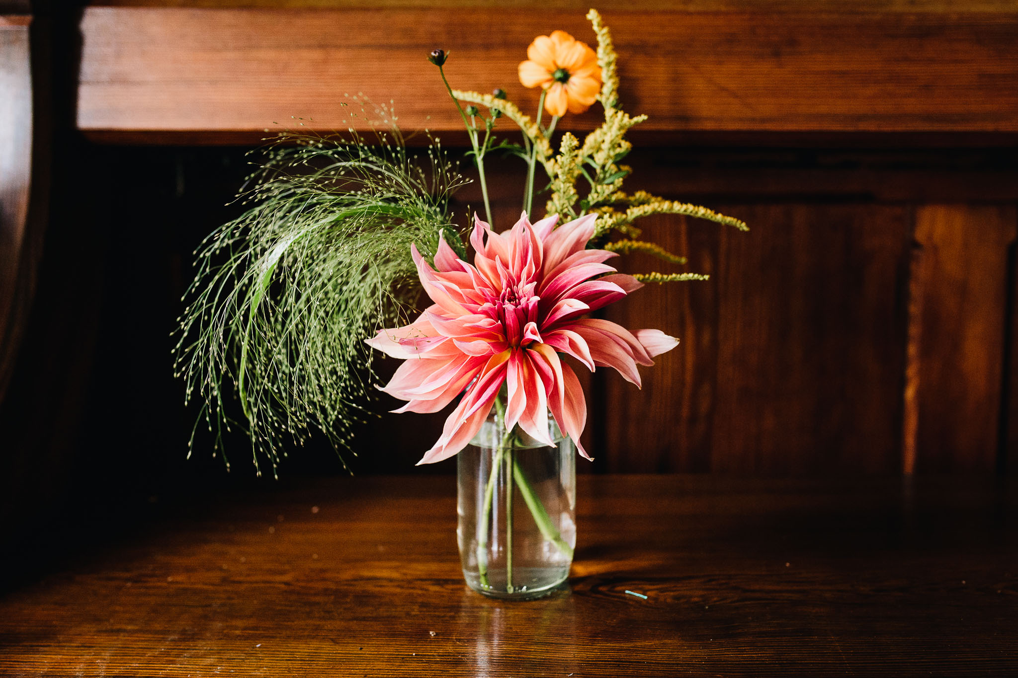 BRIGHTLY COLORED FLOWERS IN JAM JARS IN WELSH BARN