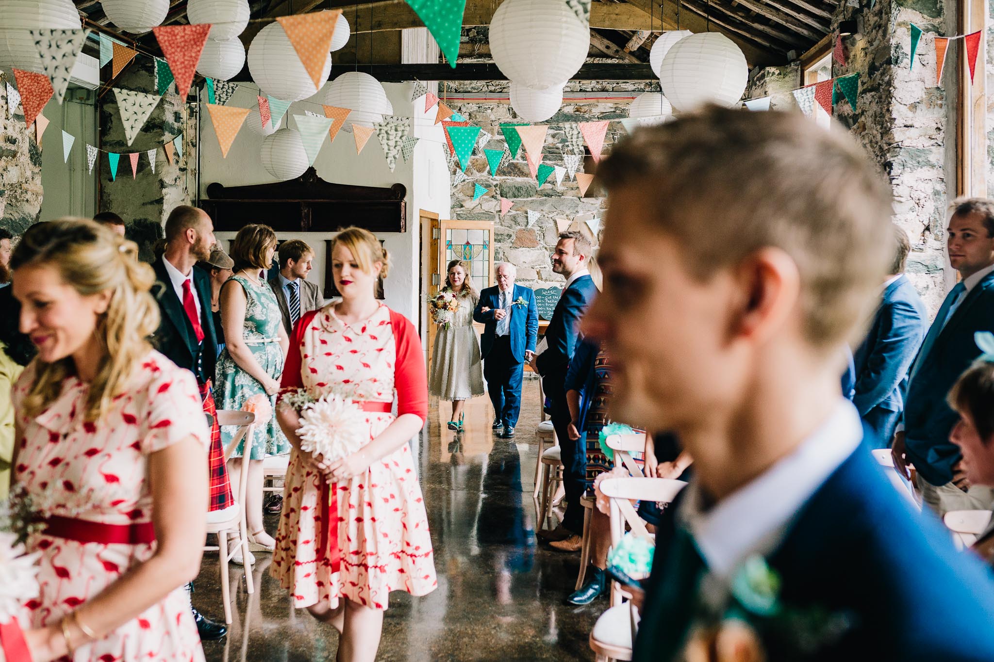 BRIDESMAIDS WEARING WHITE AND RED DRESSES WALKING IN TO WEDDING BARN