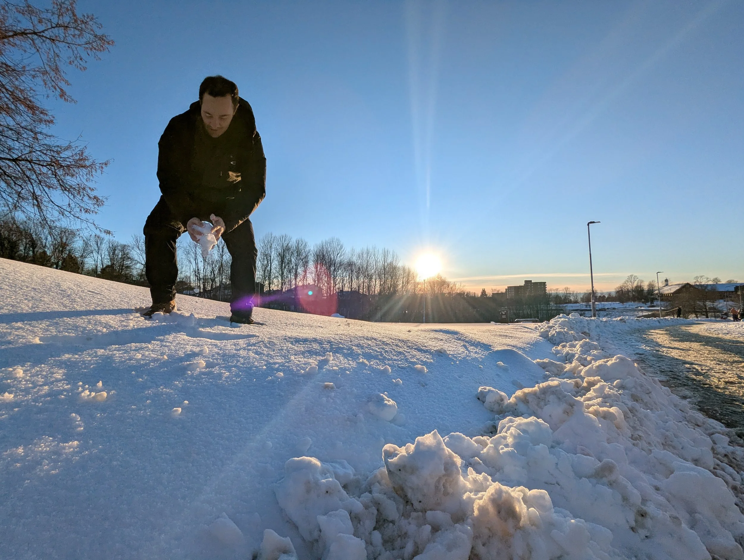 A copywriter and marketer shaping a snowball, with a setting sun in the background.