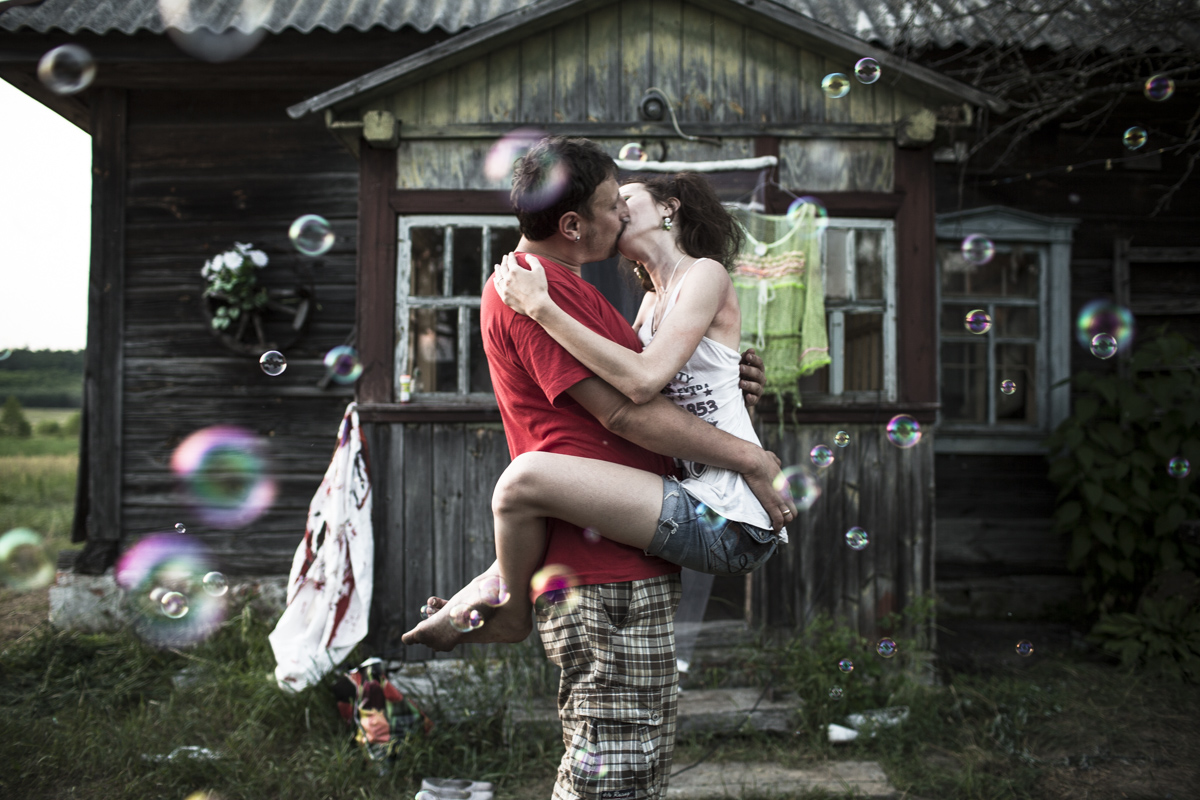 Zhenya (Evgeny) and Yulia kiss in front of their datcha during their wedding celebration with their friends.