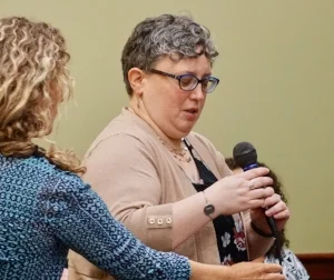 Tina Spears, L, hands Microphone to Anne LeClerc
