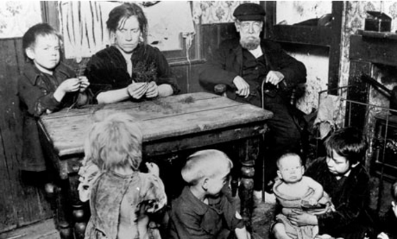 A lower class family in the Victorian period in their home. Look at the boy looking straight into the camera; that is not the face of a carefree child.