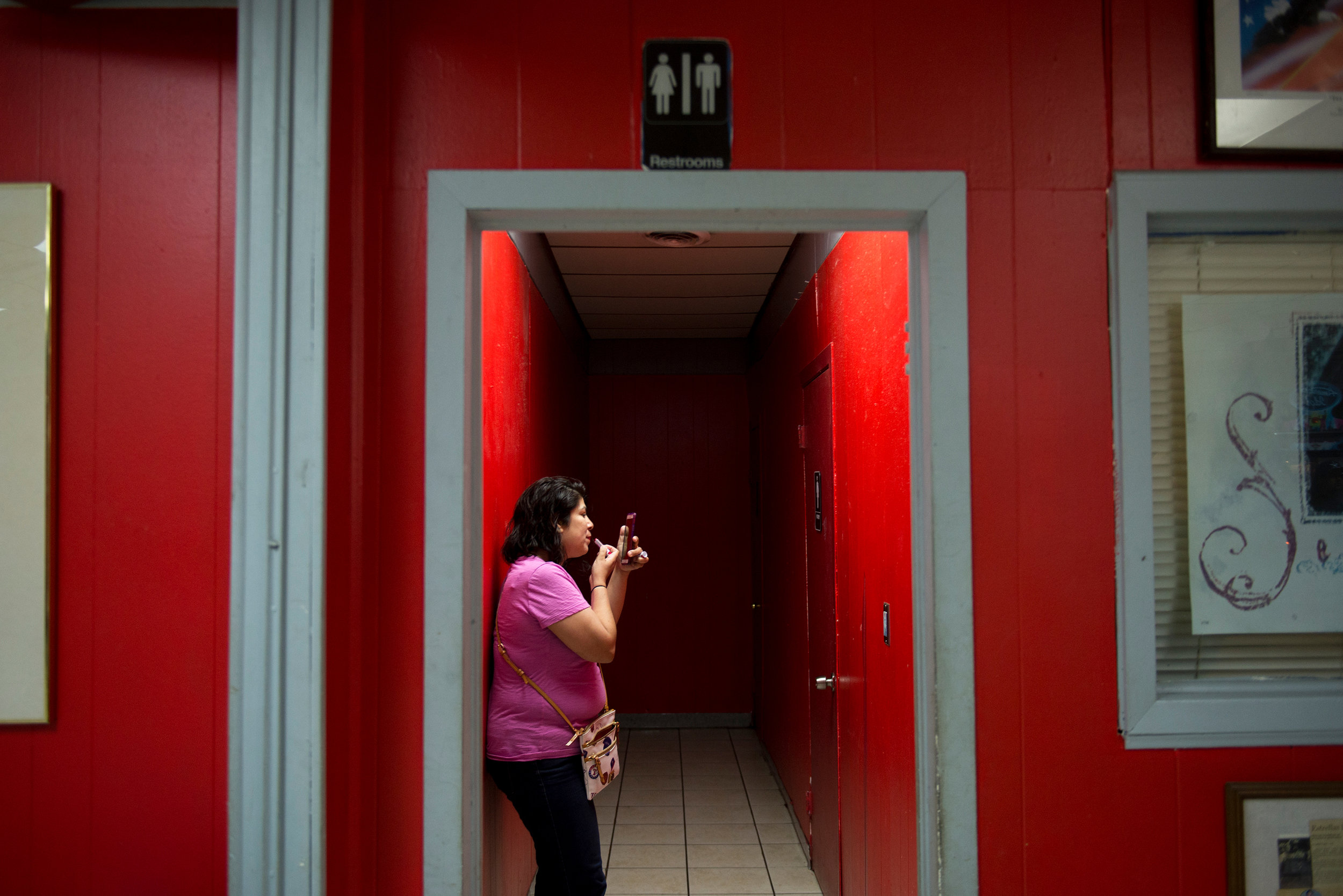 A woman checks herself with her phone's camera, applying lipstick before an event celebrating the legacy of the "Queen of Tejano," Selena Quintanilla, at Country Burger in Oak Cliff on Saturday, March 25, 2017.