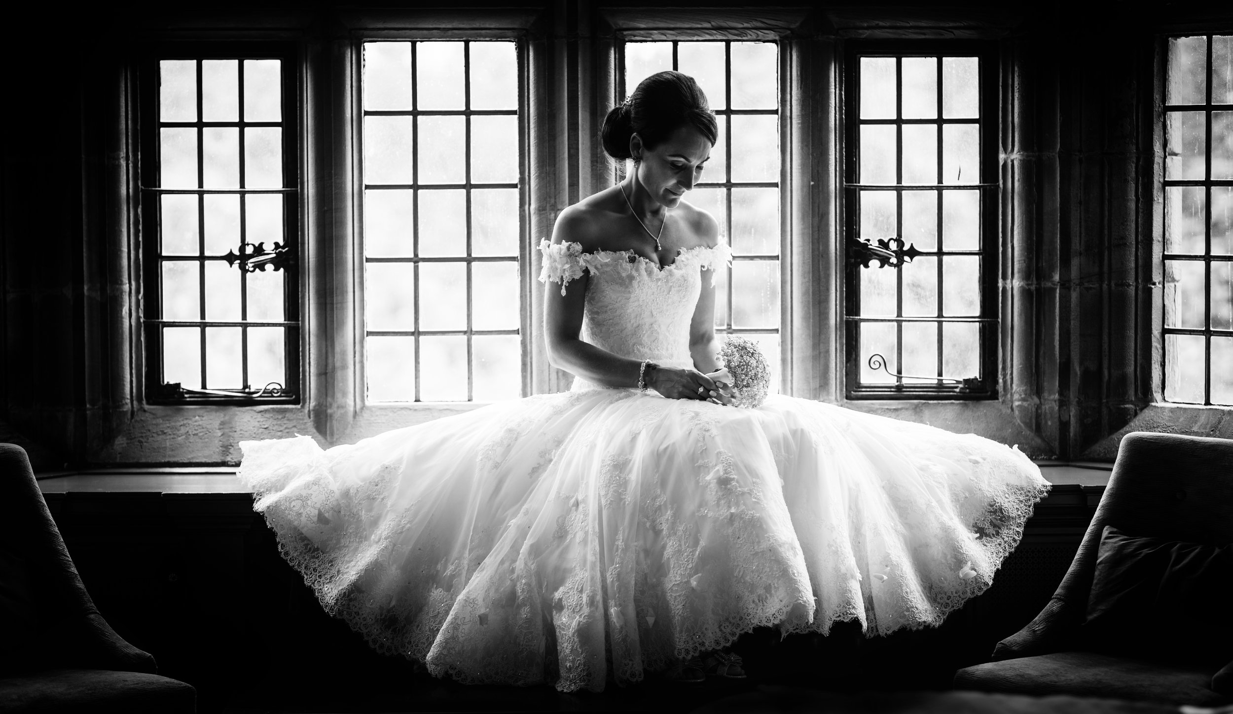 Black and White portrait of a bride sitting in a window seat