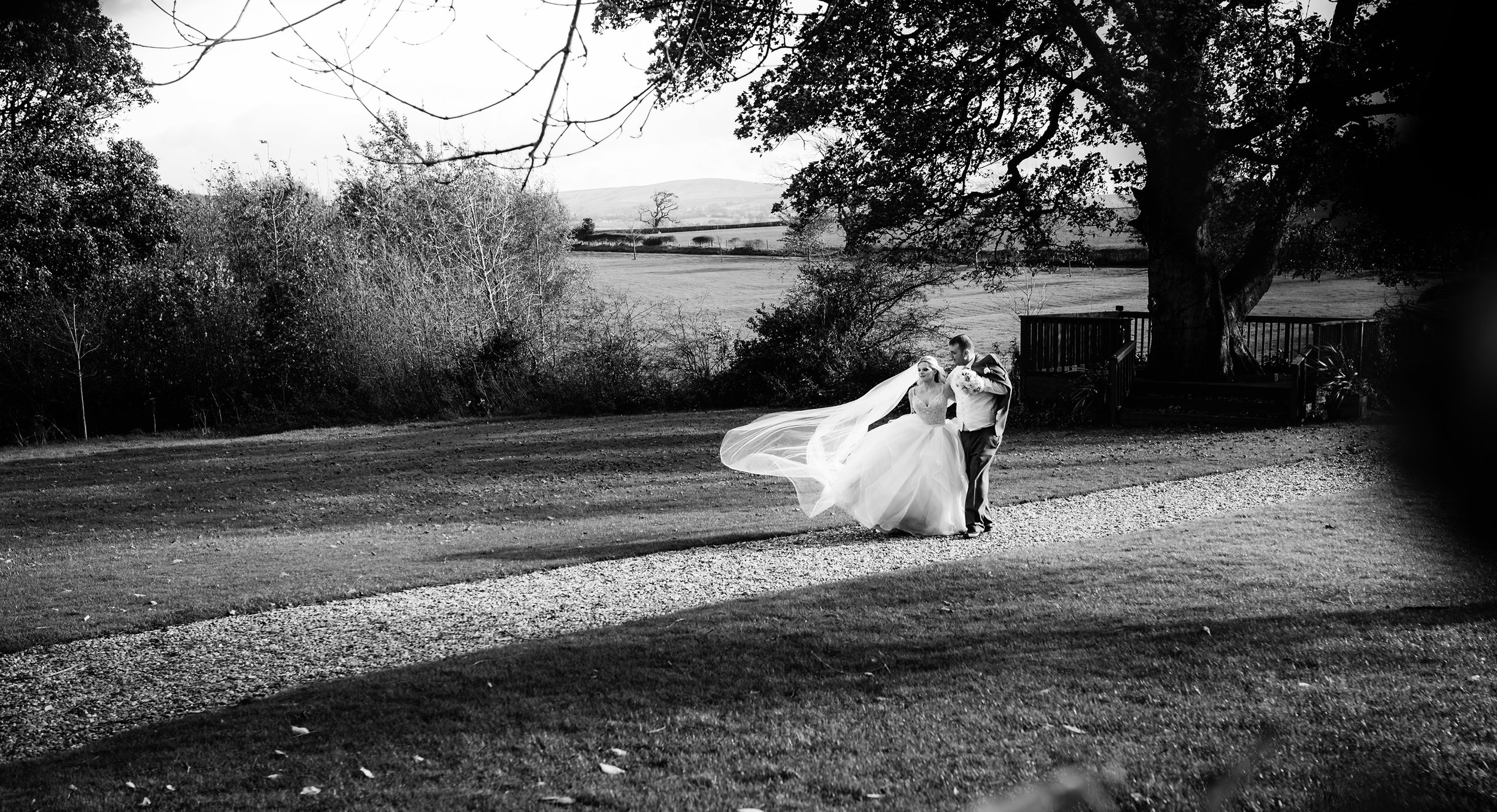 Black and white image of the bride and groom walking in the garden