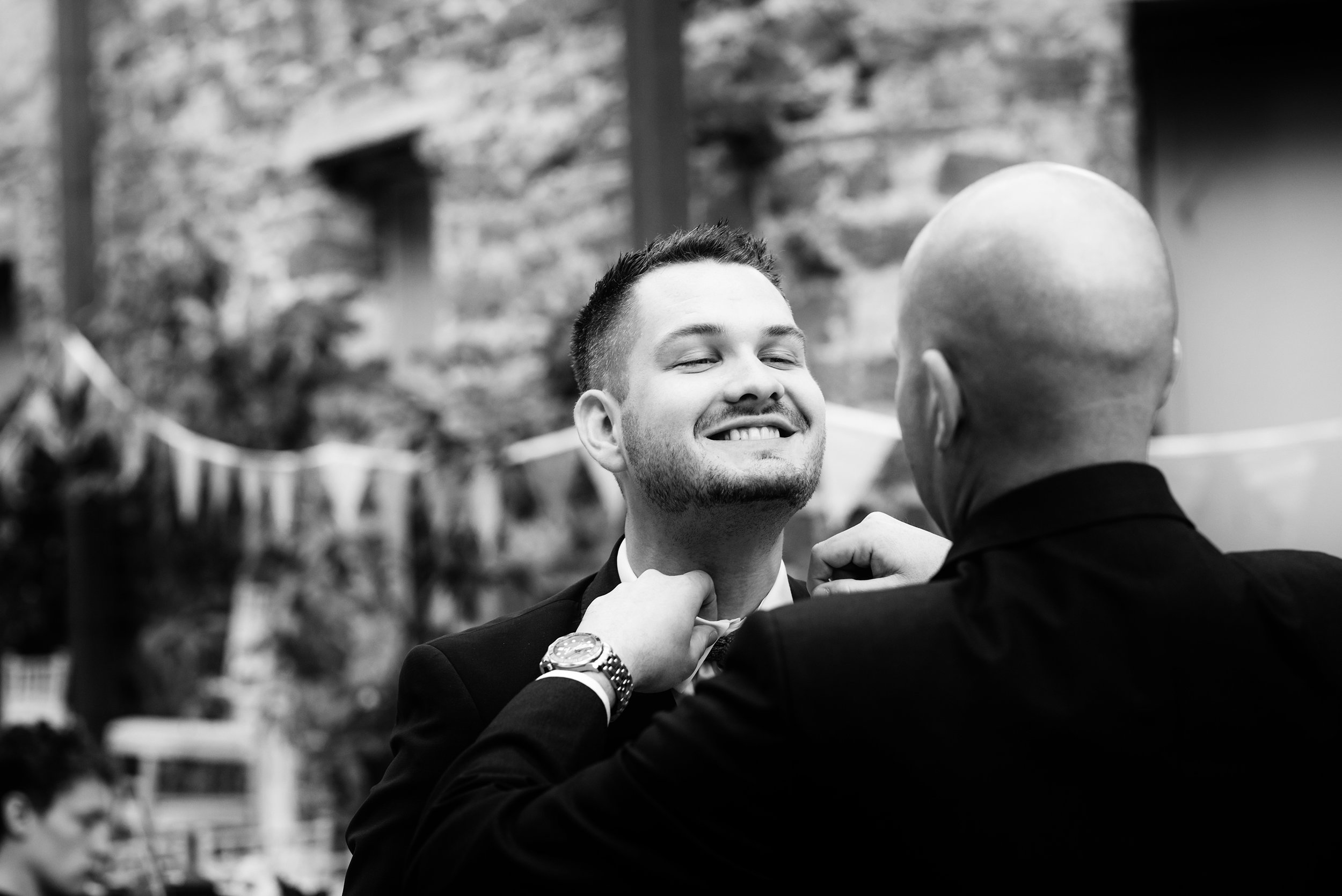 The groom getting a little help to straighten his tie