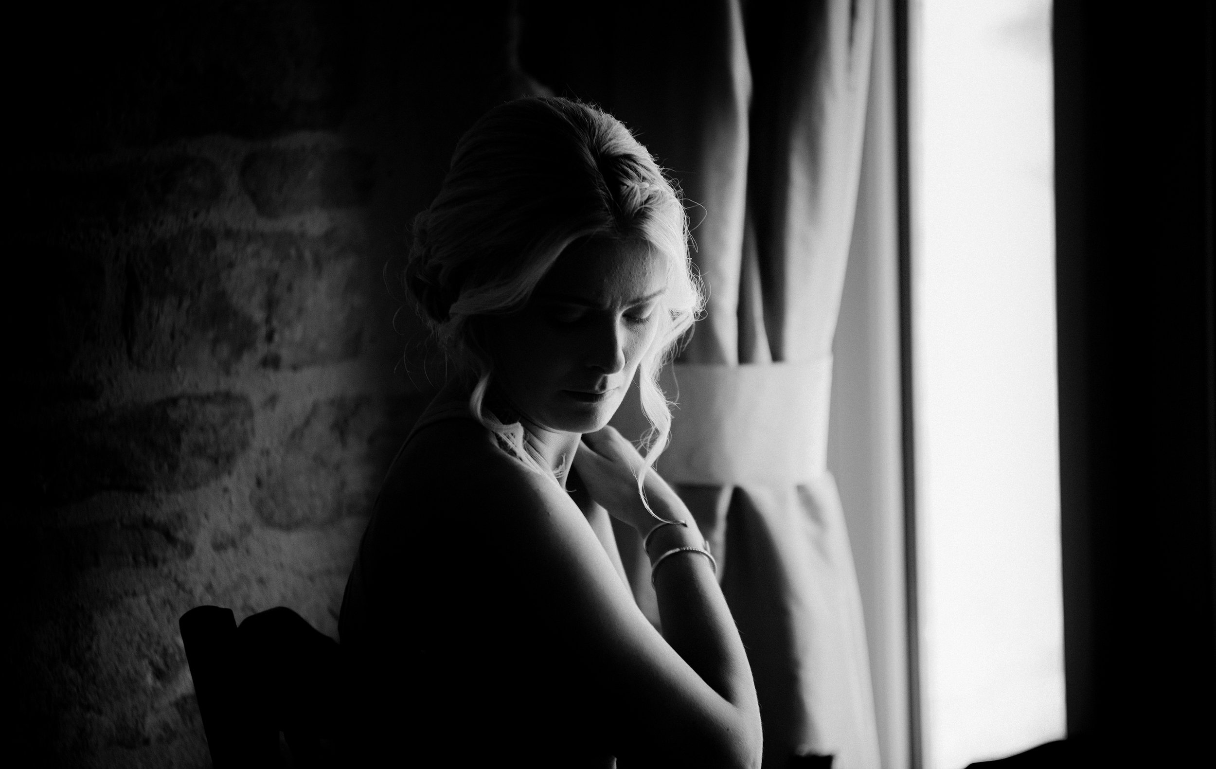 Beautiful black and white moody images of a bridesmaid in the window light