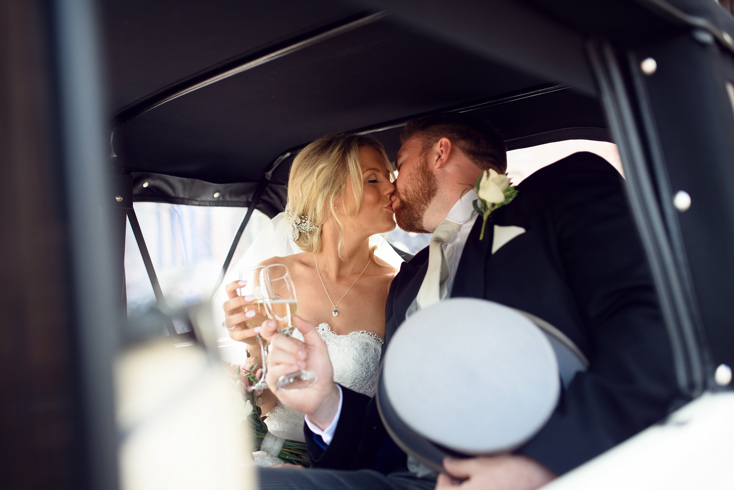 The bride and groom kissing in the back of the car