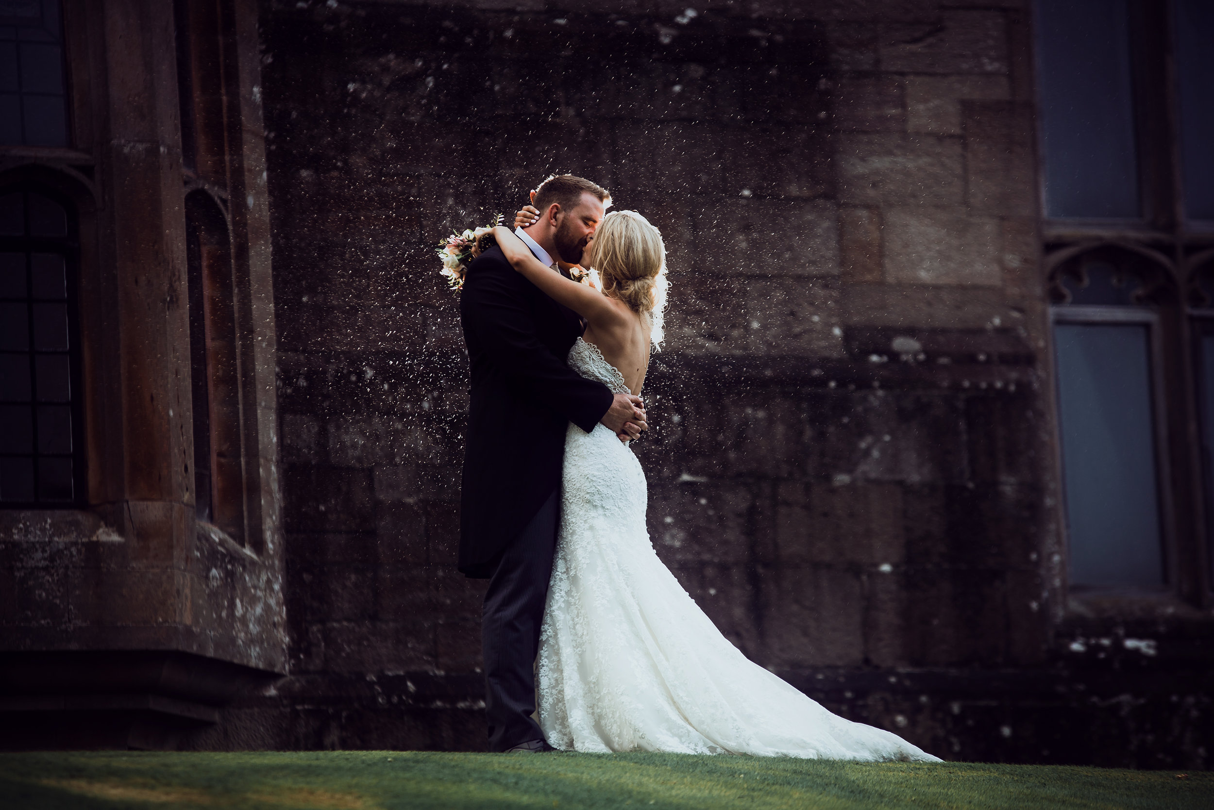 The bride and groom kissing in the rain