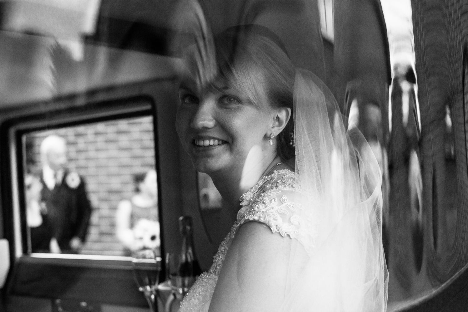 Black and white images of the bride sitting in the back of the wedding car shot through a glass window