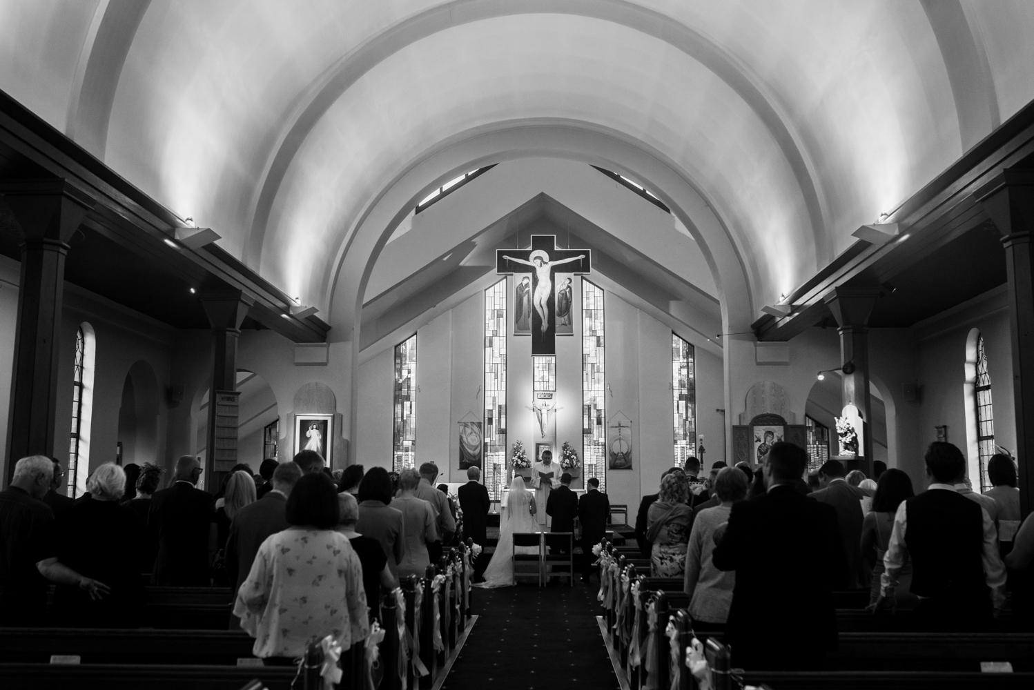 Black and white wide angle shot from the back of the church during the wedding ceremony