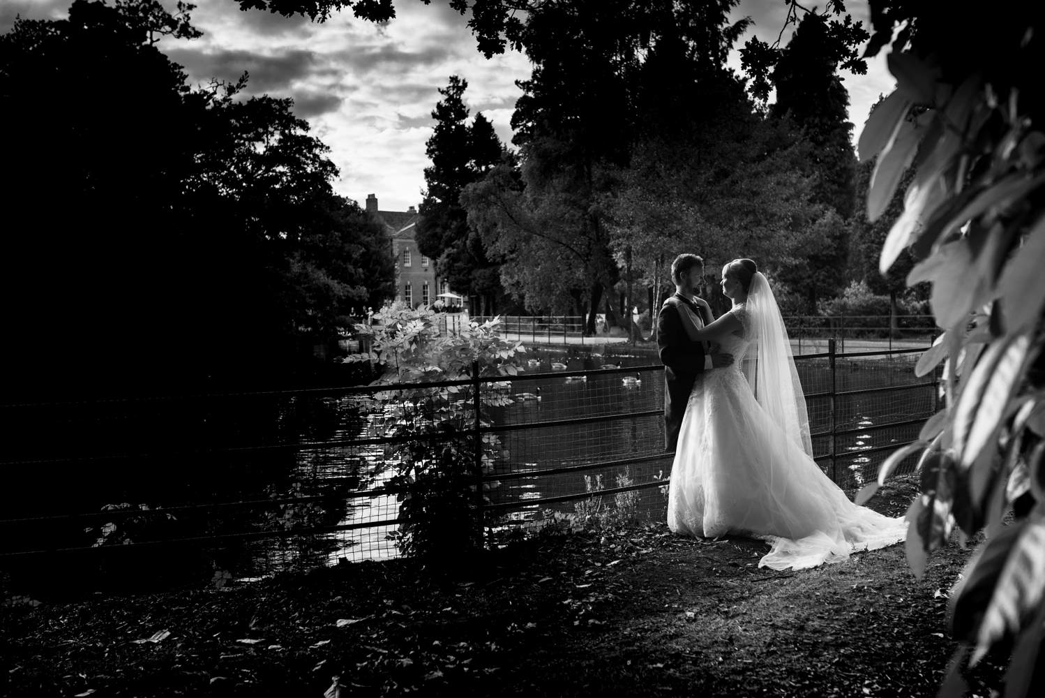 Black and white portrait of the bride and groom with the lake and hall in the background the swans even came over to say hi