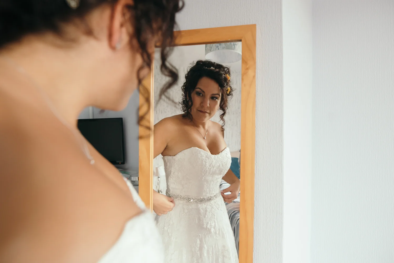 Bride adjusts her dress in a mirror during bridal preparations