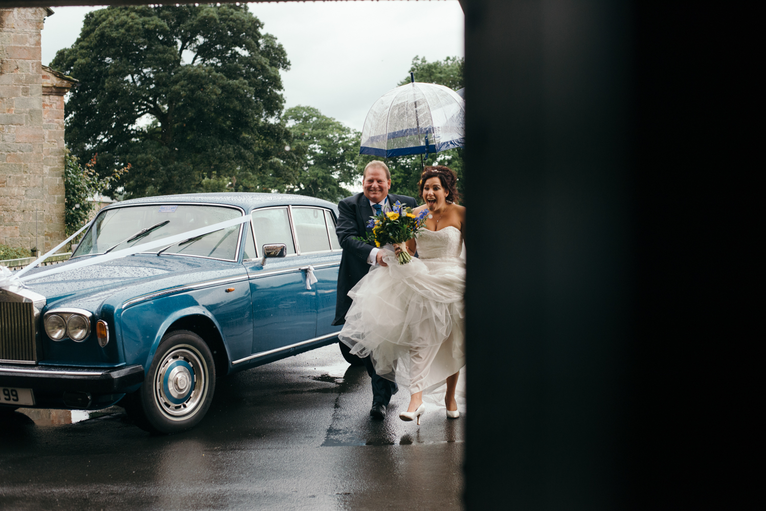 Bride and her father running into church out of the rain