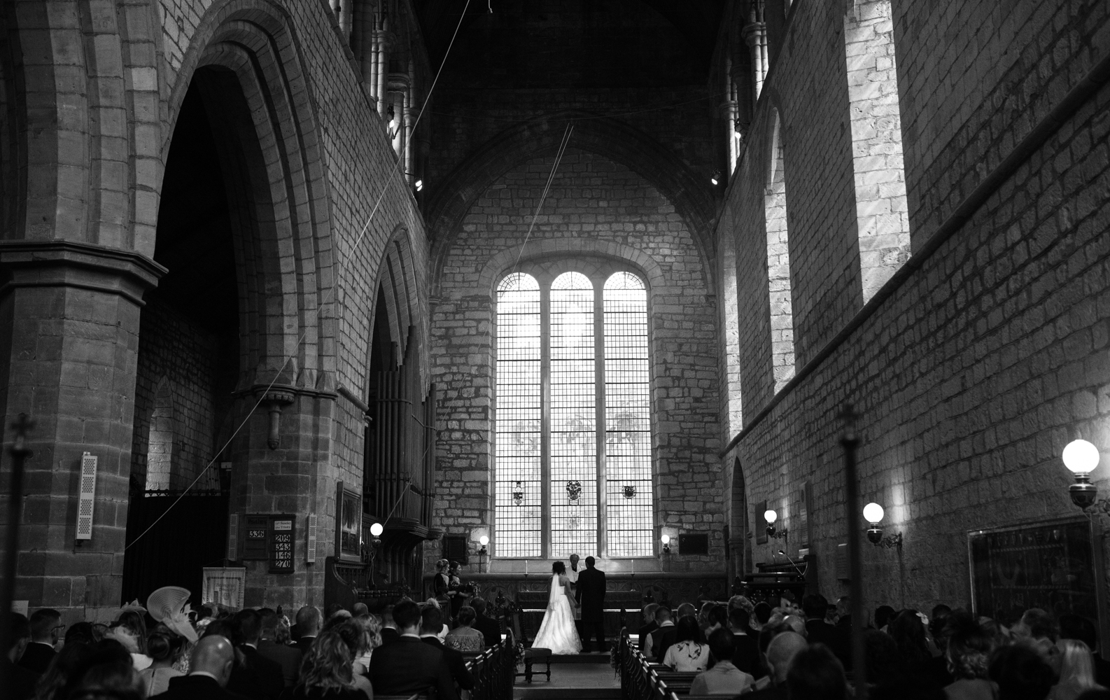 black and white image of the bride and groom from the very back of the priory