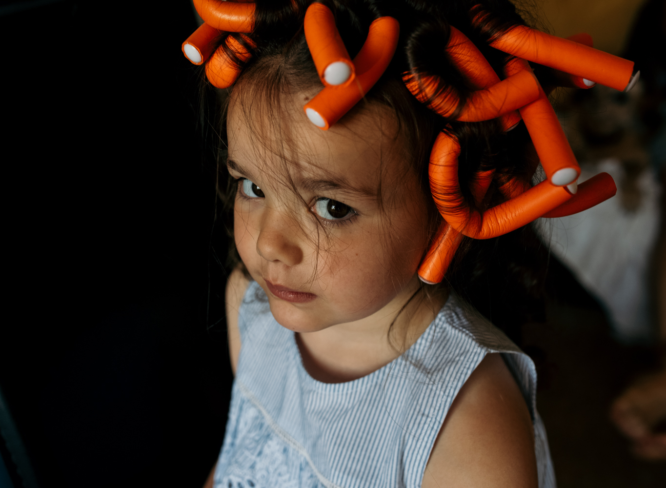 A little bridesmaid with curlers in her hair during bridal preparations