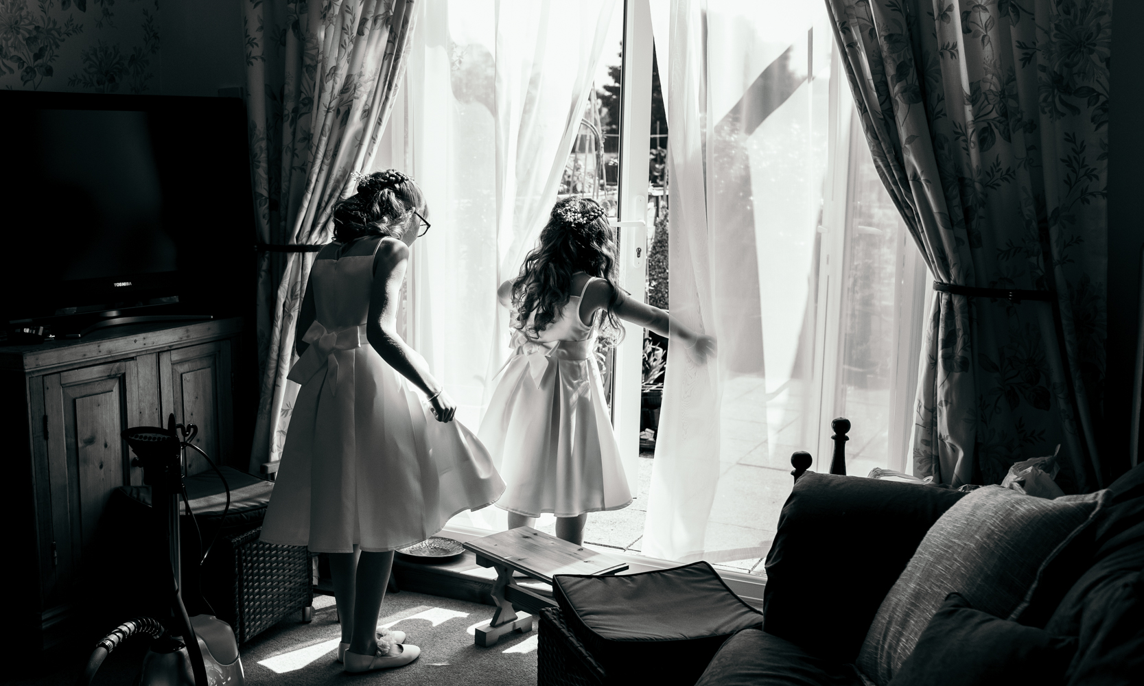 Black and white photo of two young bridesmaids playing during bridal preparations
