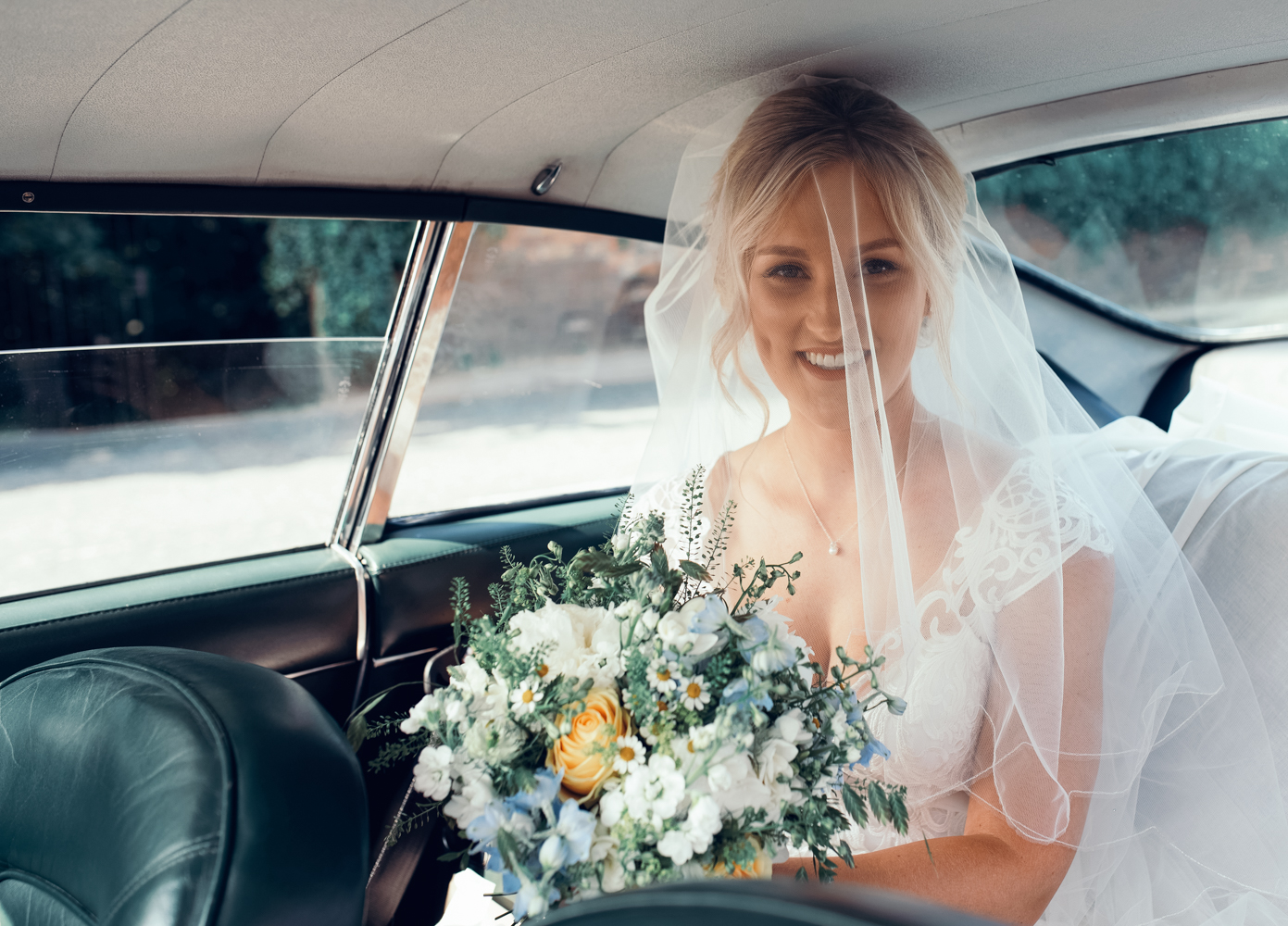 The bride sitting in the back of the Aston Martin as she arrives at the church