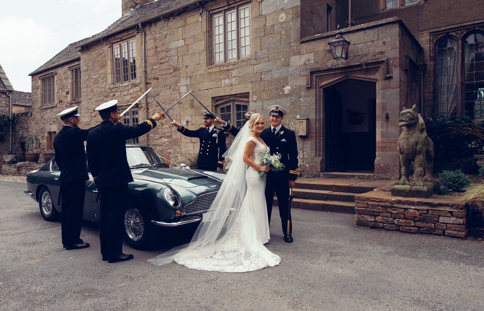 Guard of honour with the bride and groom and Aston Martin