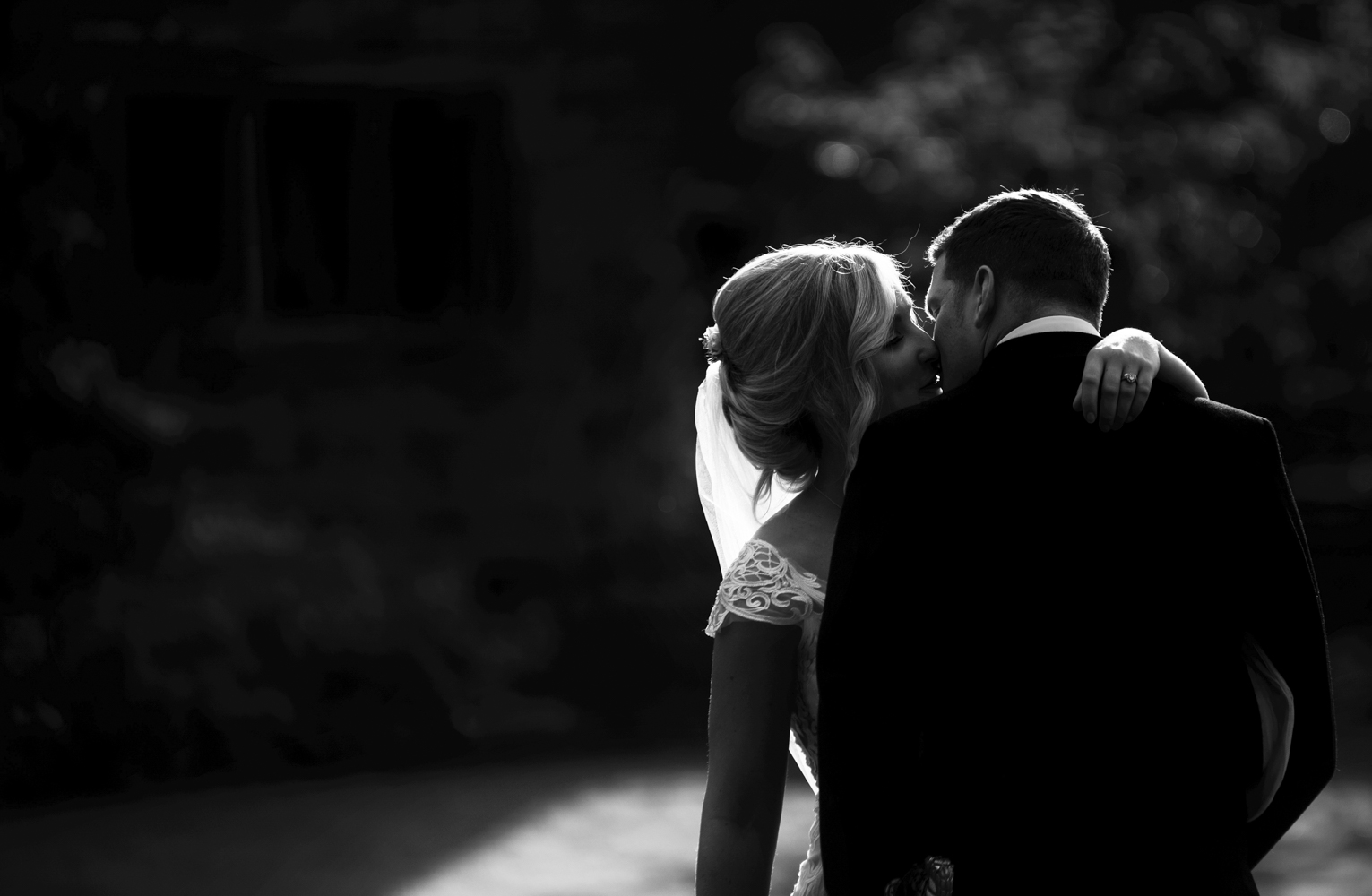 Black and white photo of the bride and groom kissing low key image