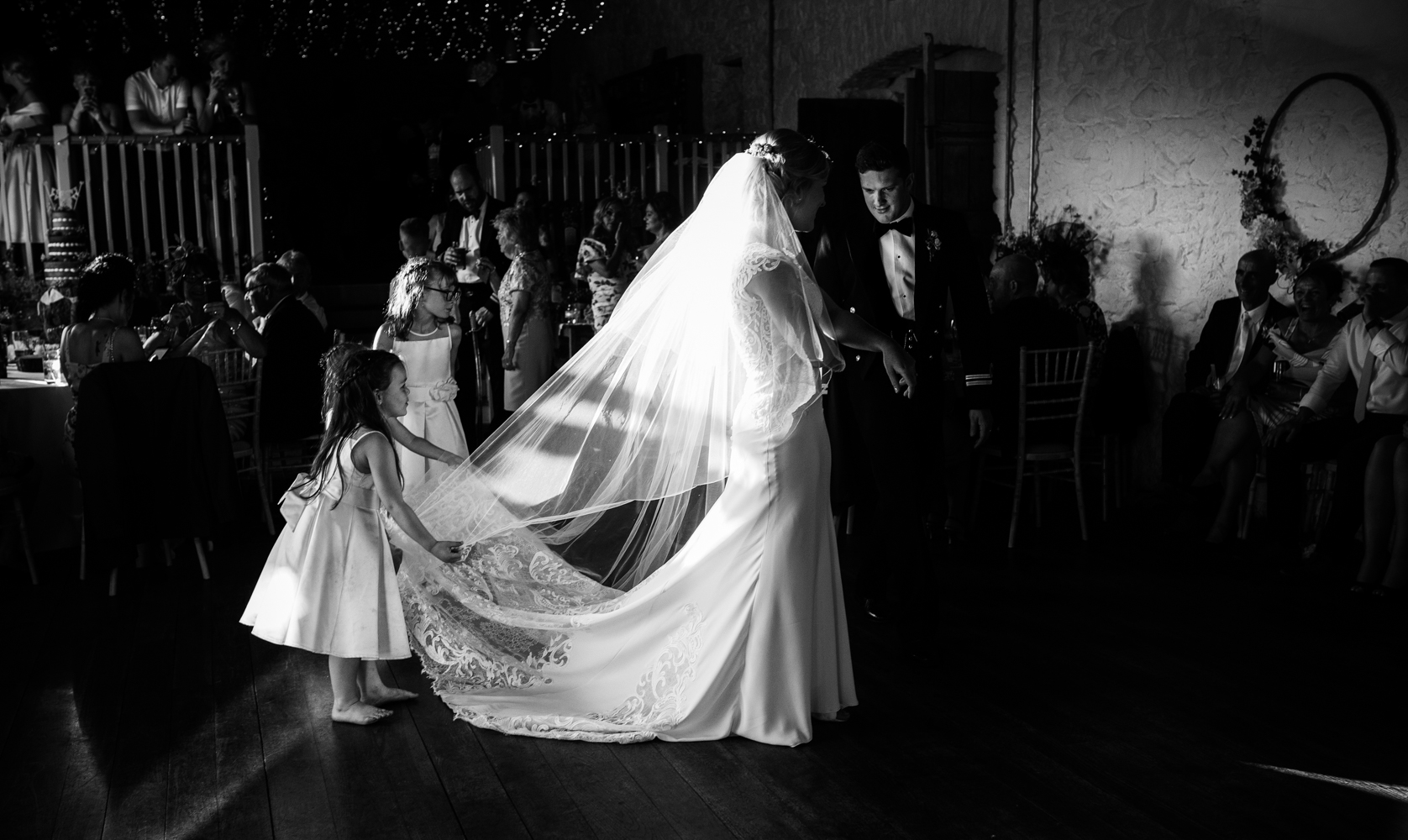 The tow young bridesmaids help the bride arrange her dress before the first dance