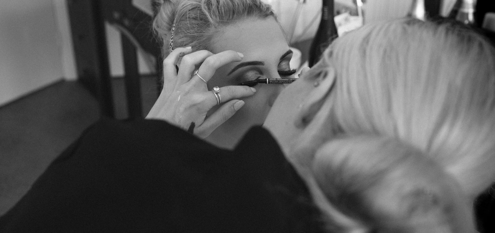 Black and white image of the bride having her eye makeup applied