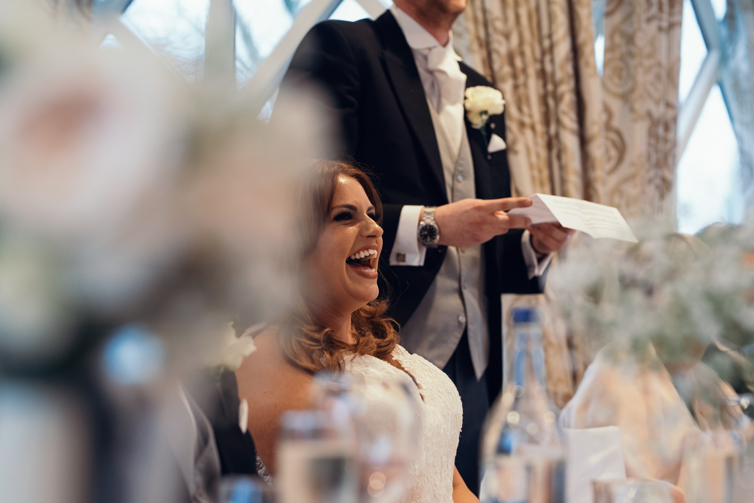 The bride laughing at one of the grooms joke during the speeches