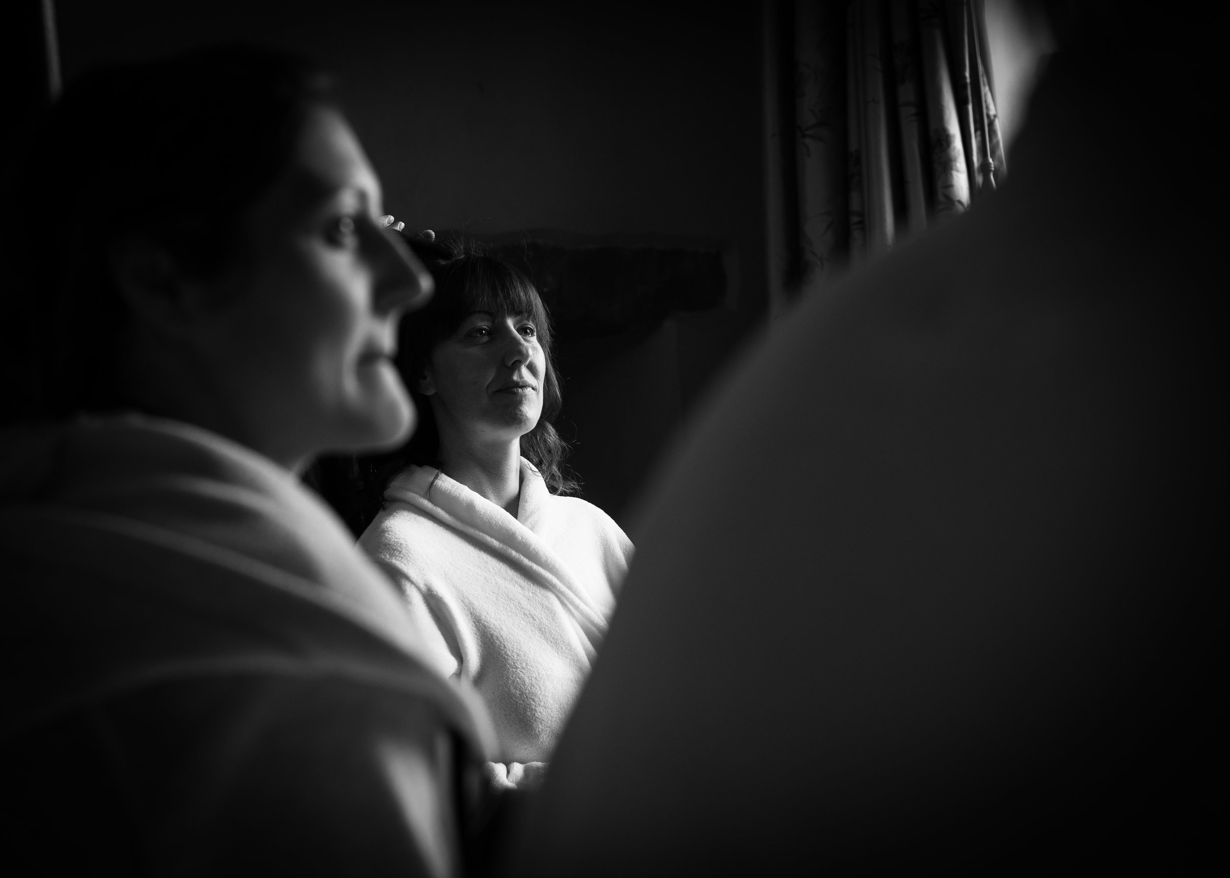 Black and white photo of the bride sitting having hair and makeup done