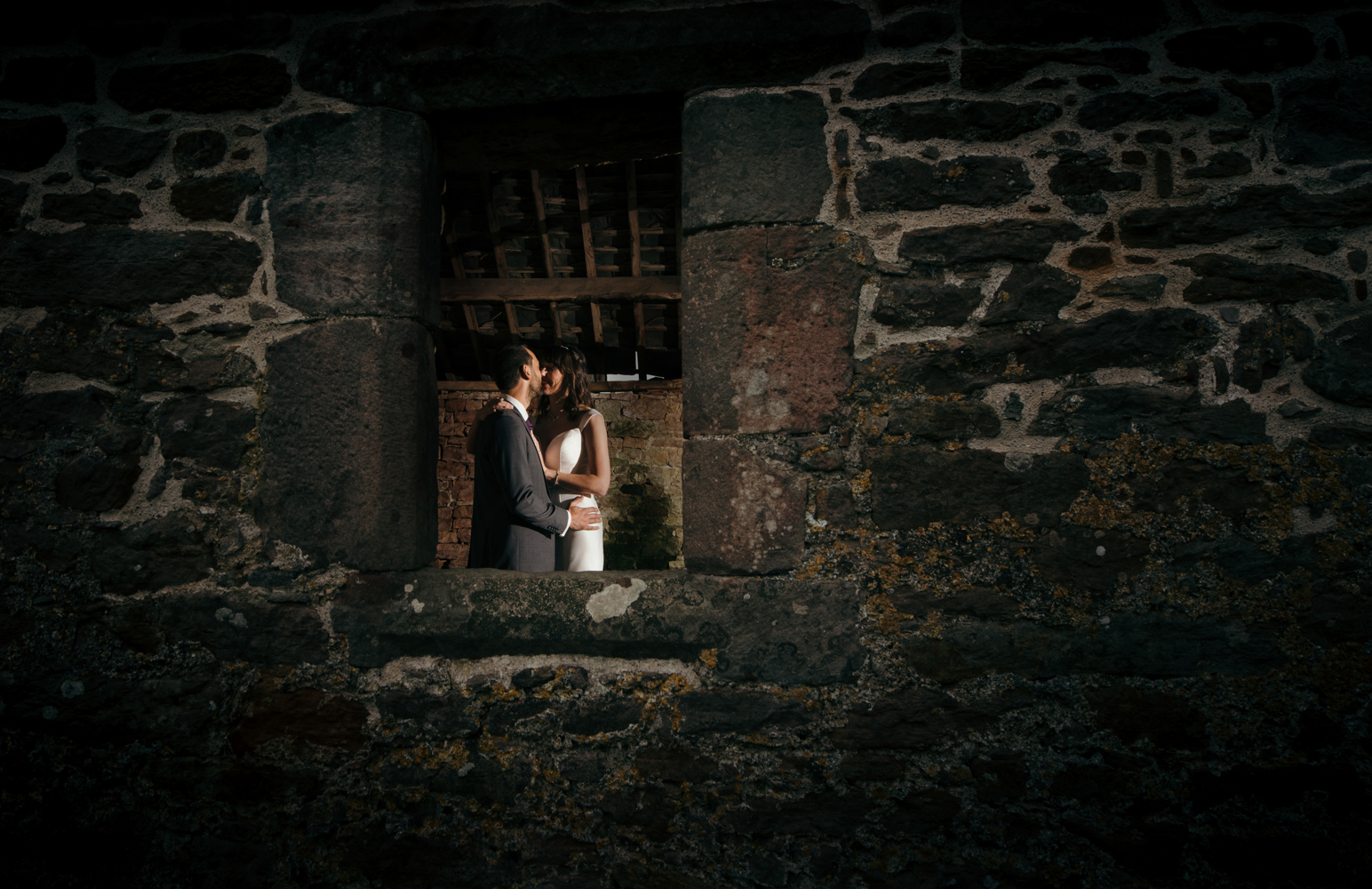 The bride and groom standing in a window having a cuddle