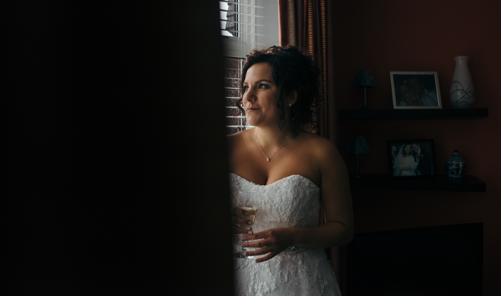 The bride looking out of the living room window waiting for the cars to arrive