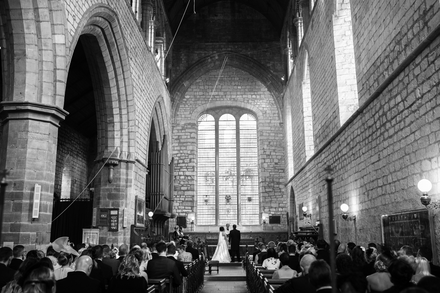 A wide angle black and white image taken from the very back of the church looking back towards the alter during preyers