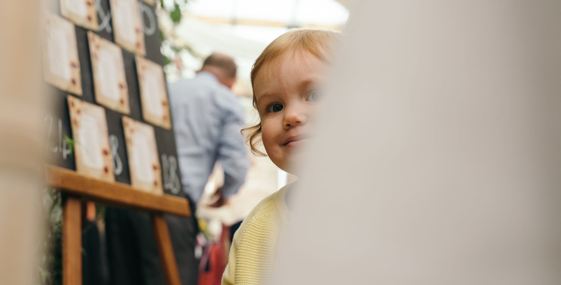 A little bridesmaid peeking around a table