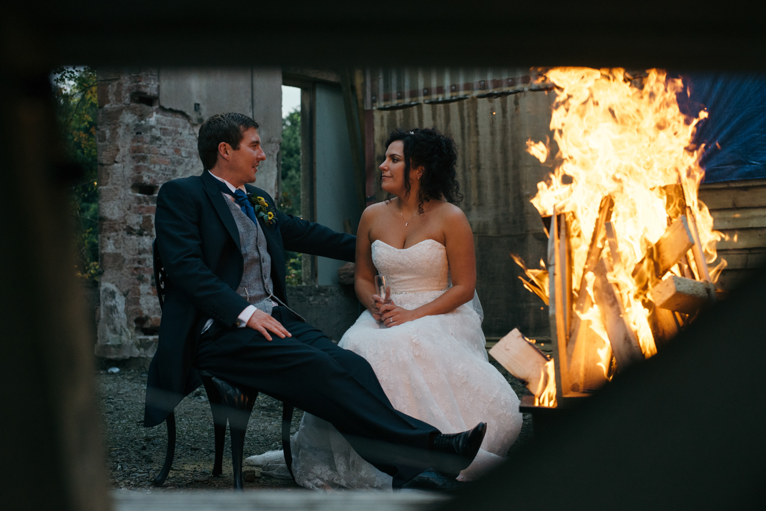 The bride and groom sitting chatting by one of the outdoor fire pits