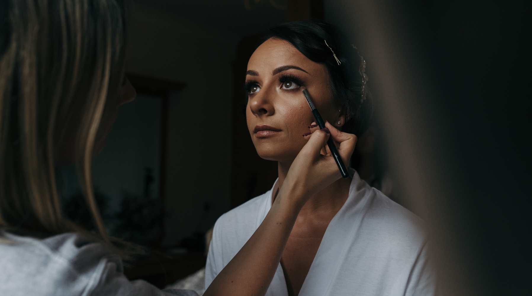 The bride having makeup done during morning preparations