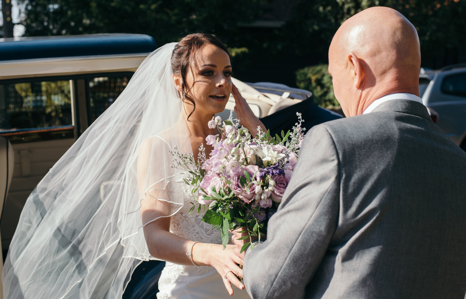 The bride and her father as she gets out of the car at church