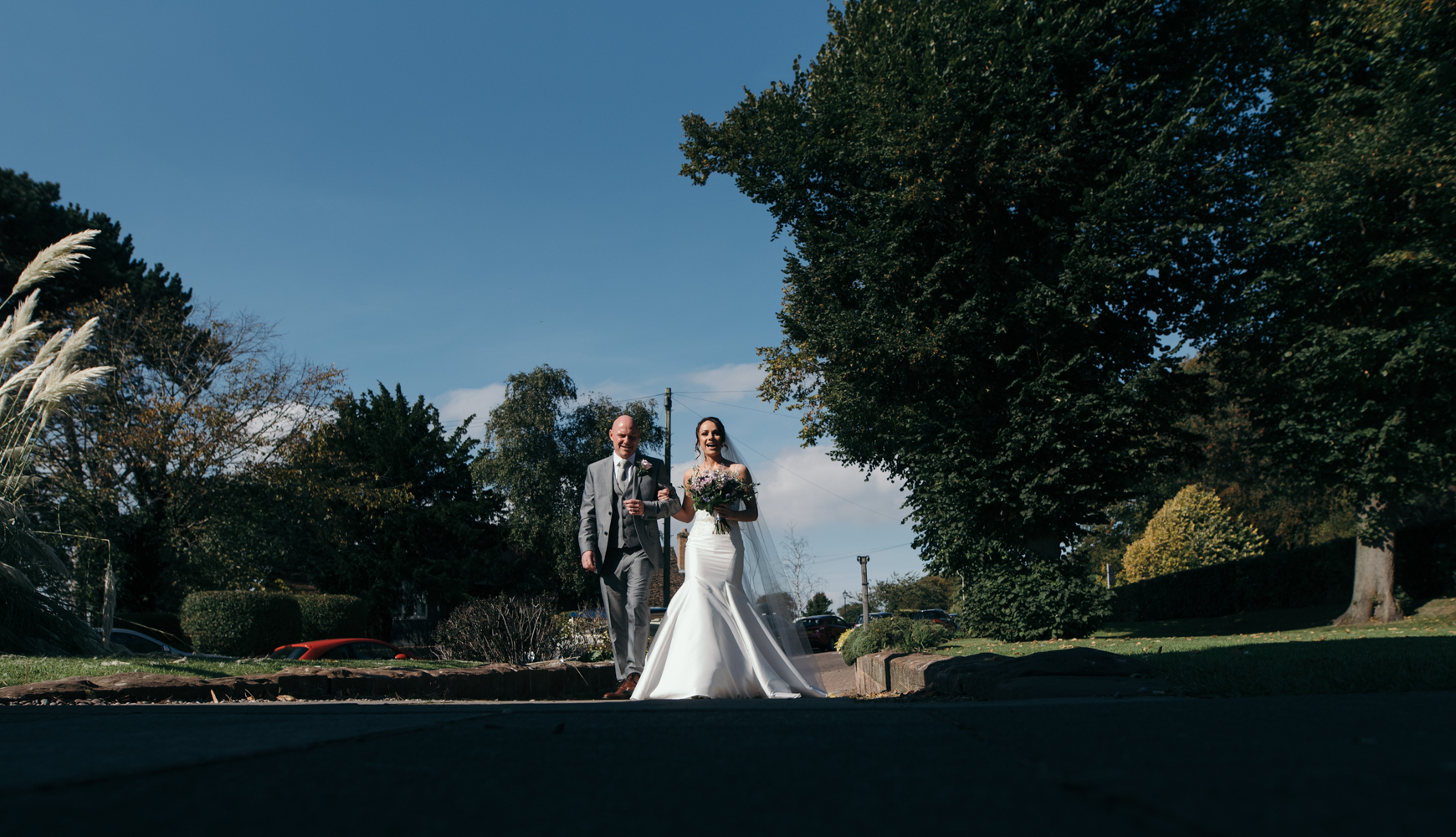 The bride and her father walking up the path to church