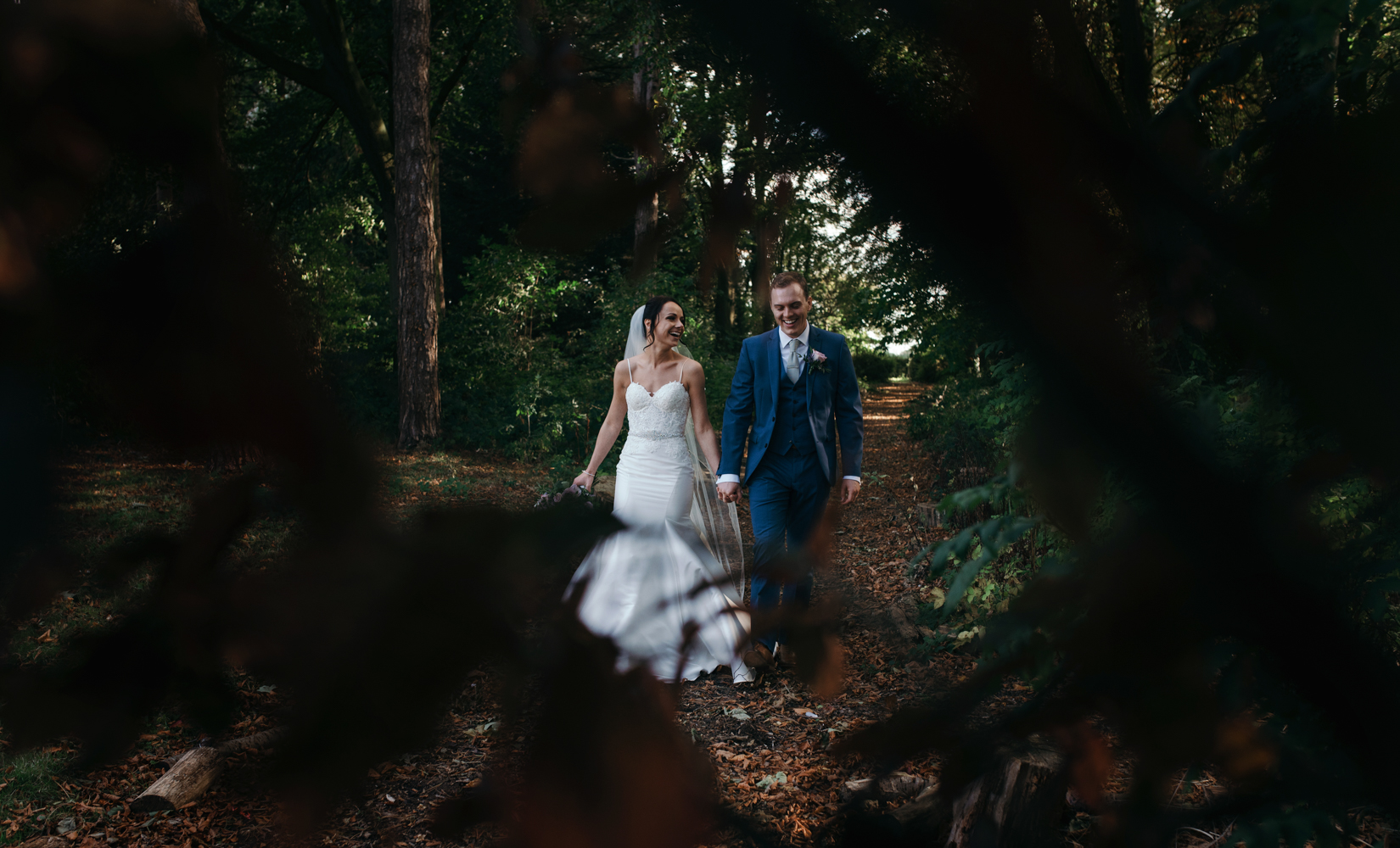 The bride and groom walking in the woods at Inglewood Manor