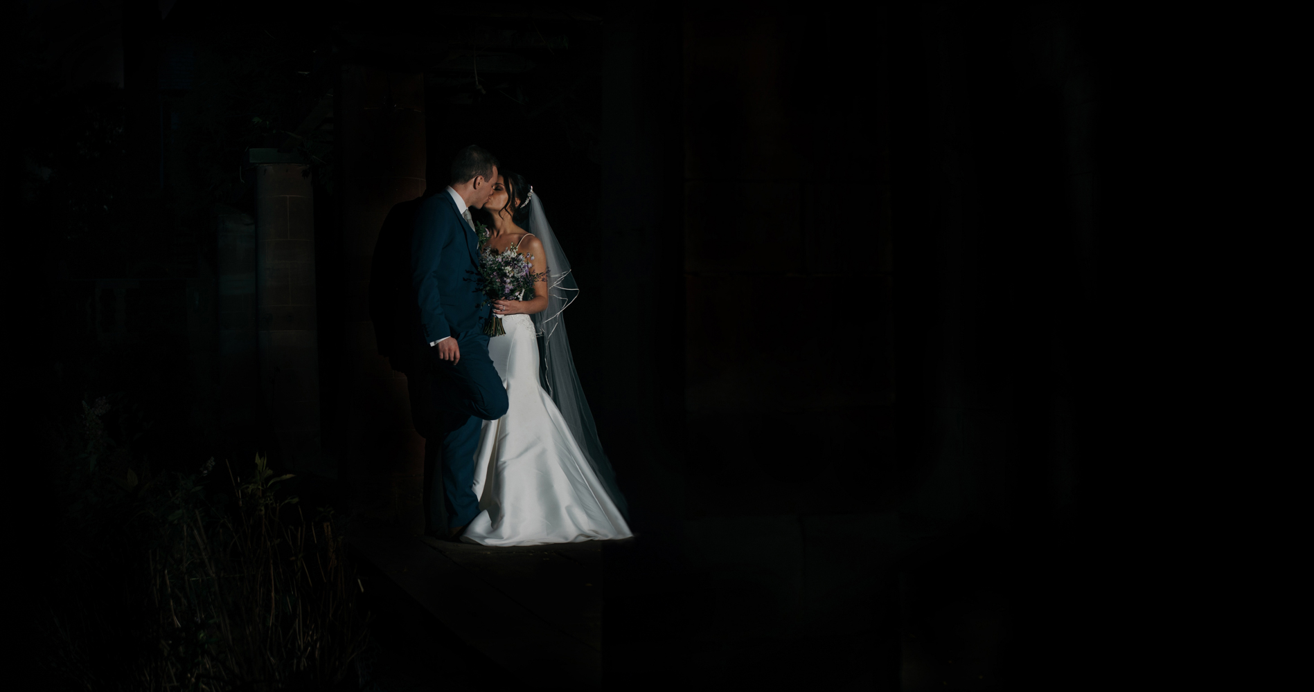 A dark and moody photograph of the bride and groom taken at night time