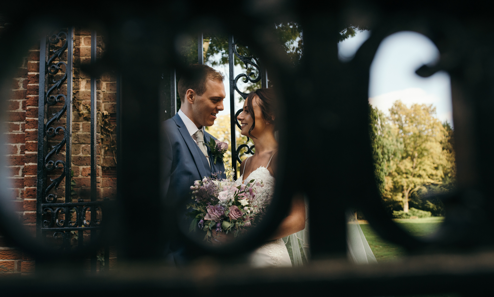 An image of the happy couple taken through the railings of the wrought iron gates