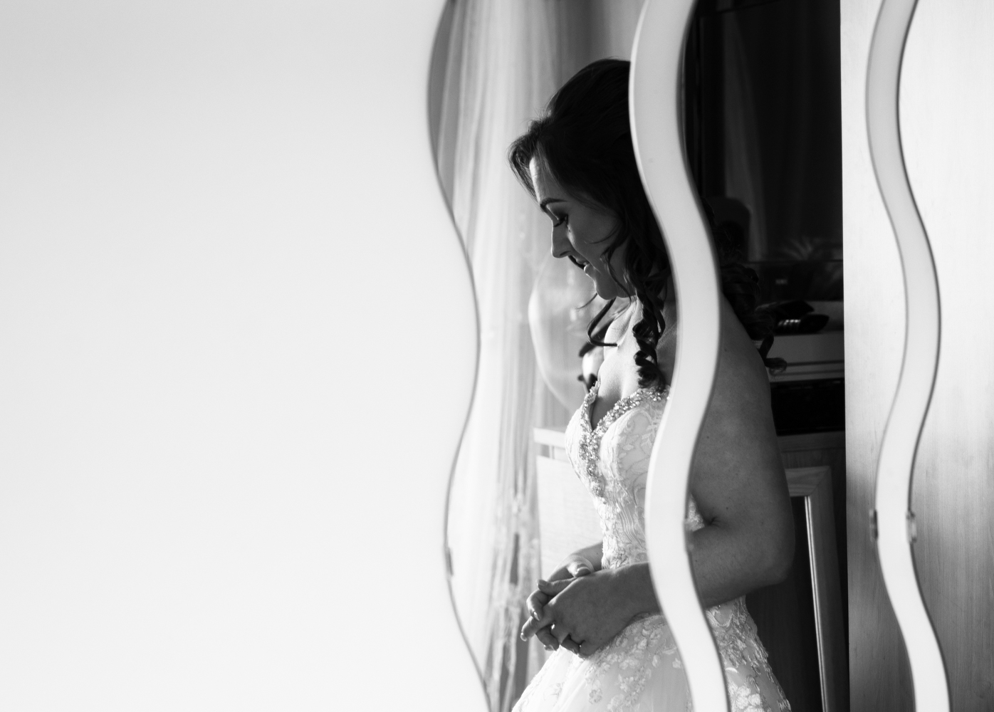 A black and white image of the bride reflected in a quirky wall mirror